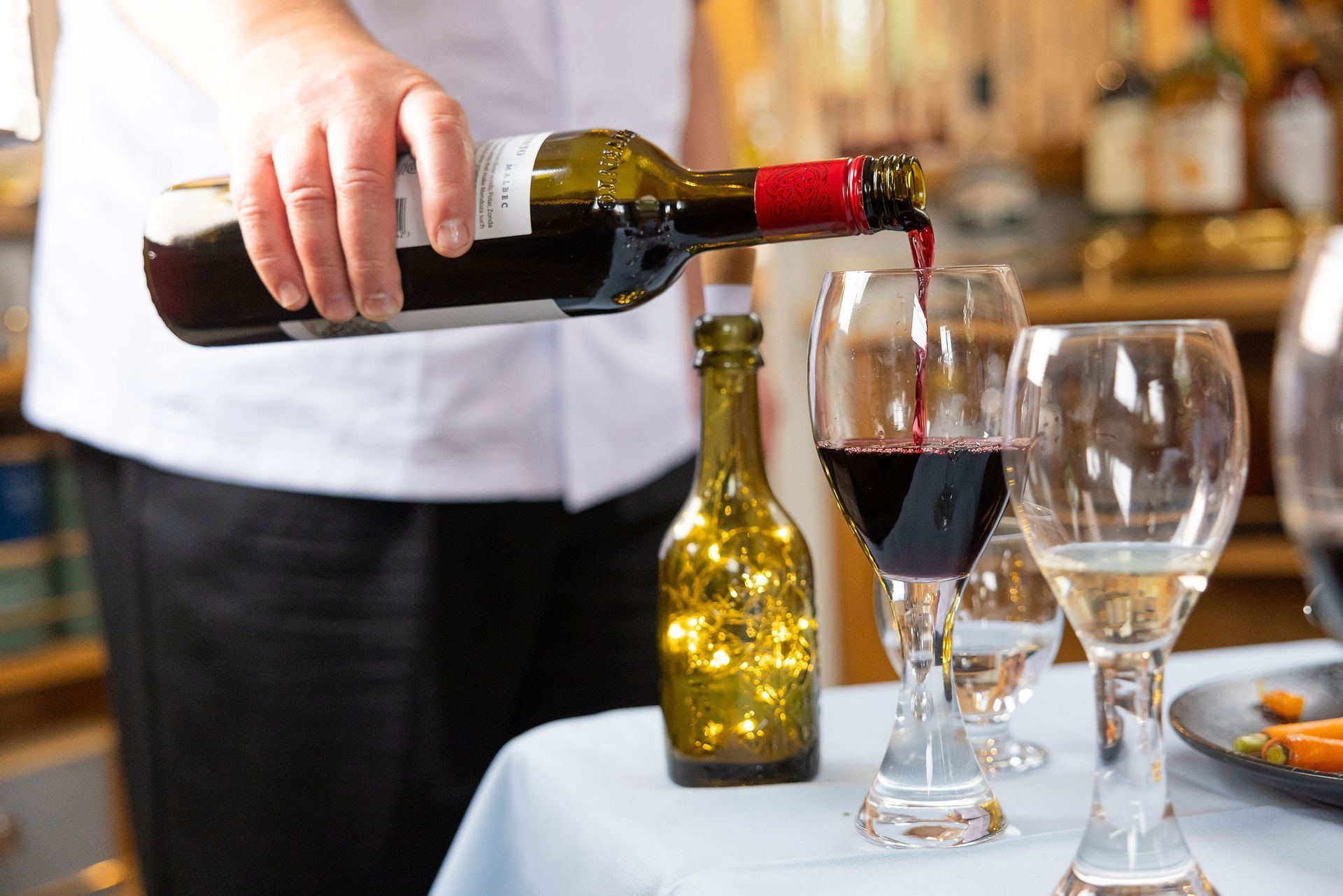 A person is pouring wine into a glass on a table.