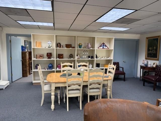 Quiet dining room with a long table, white chairs, shelves, and blue-gray walls