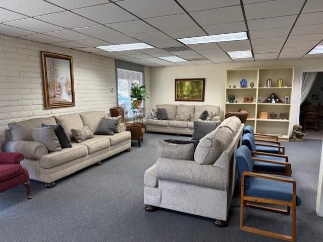 Office waiting room with beige sofas, gray chairs, and framed wall art under fluorescent lights