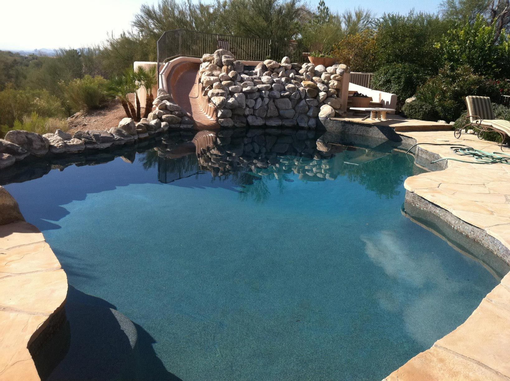 A large swimming pool with a slide in the background