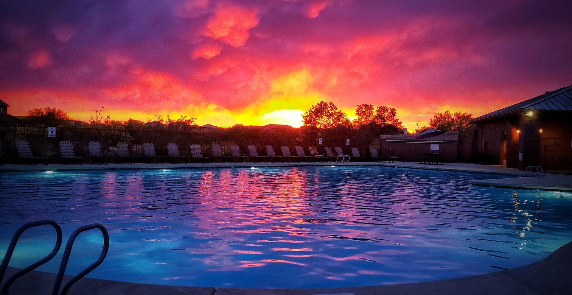 A swimming pool with a sunset in the background.