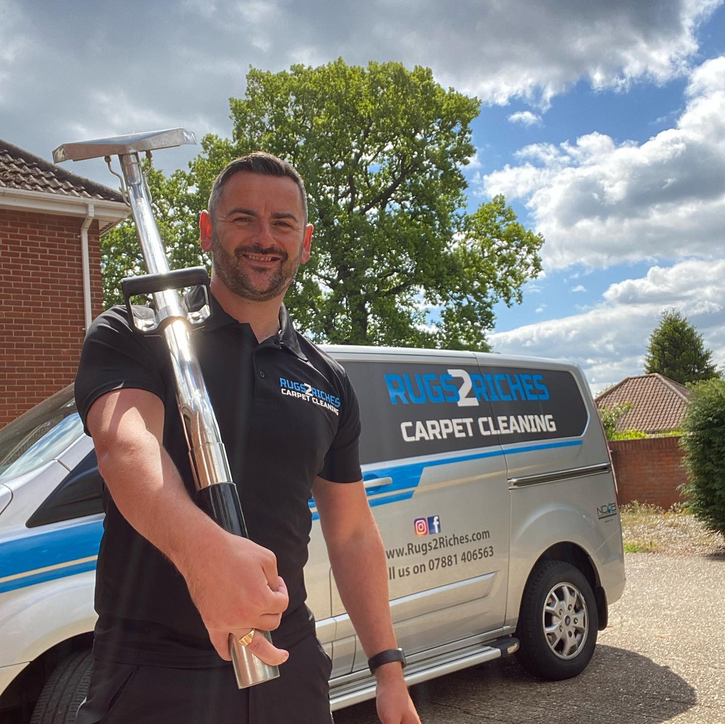 a man is standing in front of a carpet cleaning van holding a vacuum cleaner .
