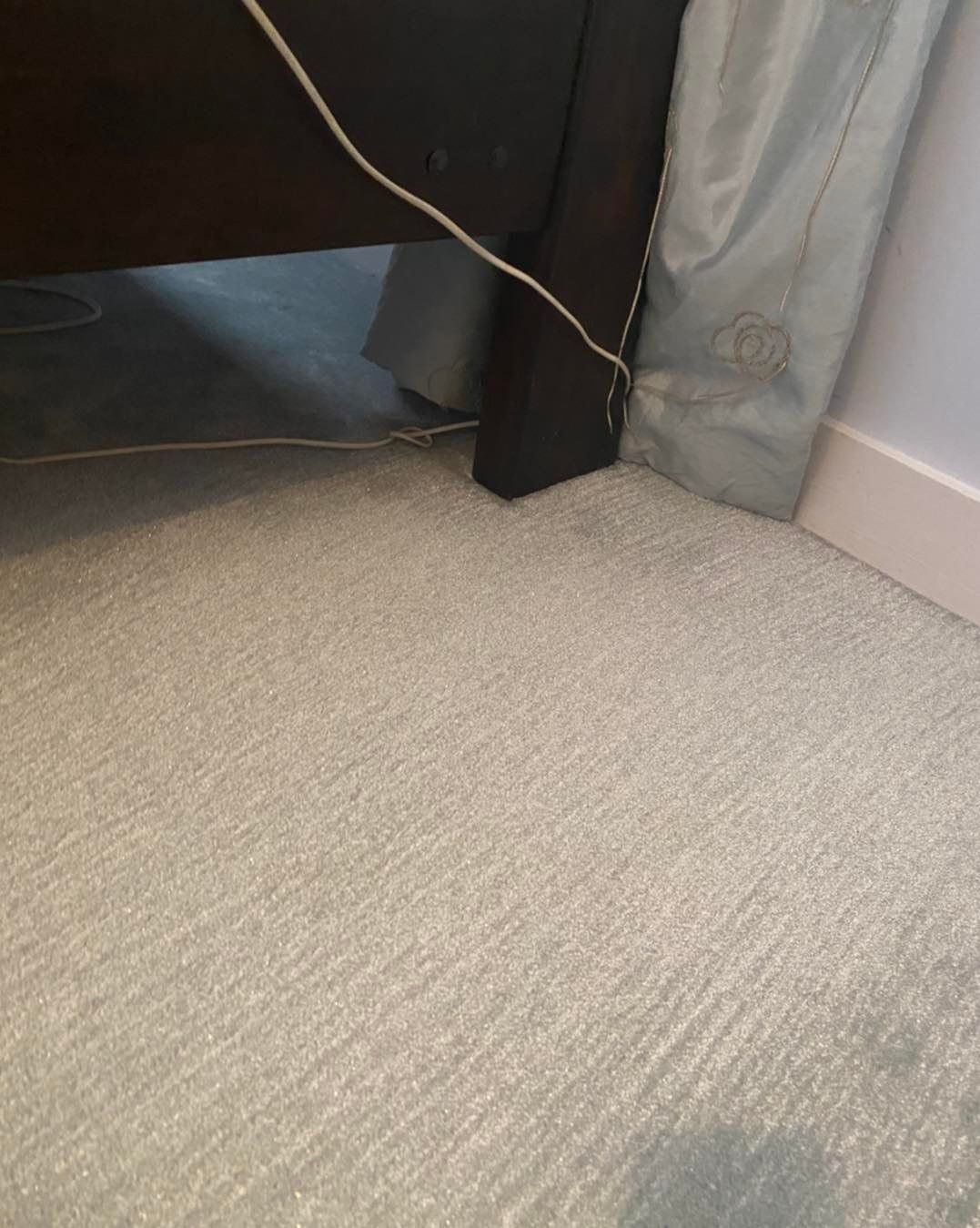 a close up of a carpeted floor next to a bed .