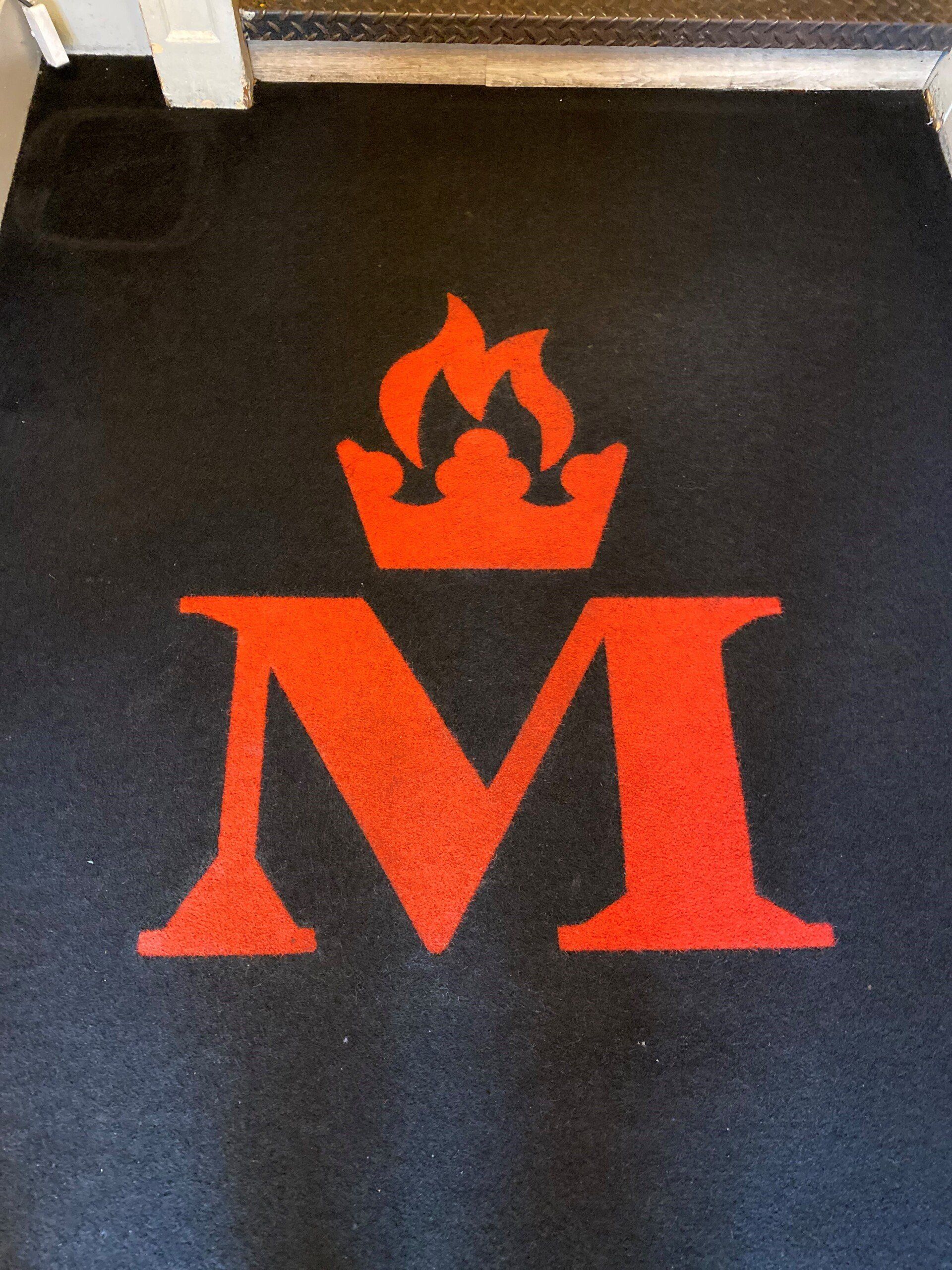a rug with red letter m with a crown on it, after cleaning