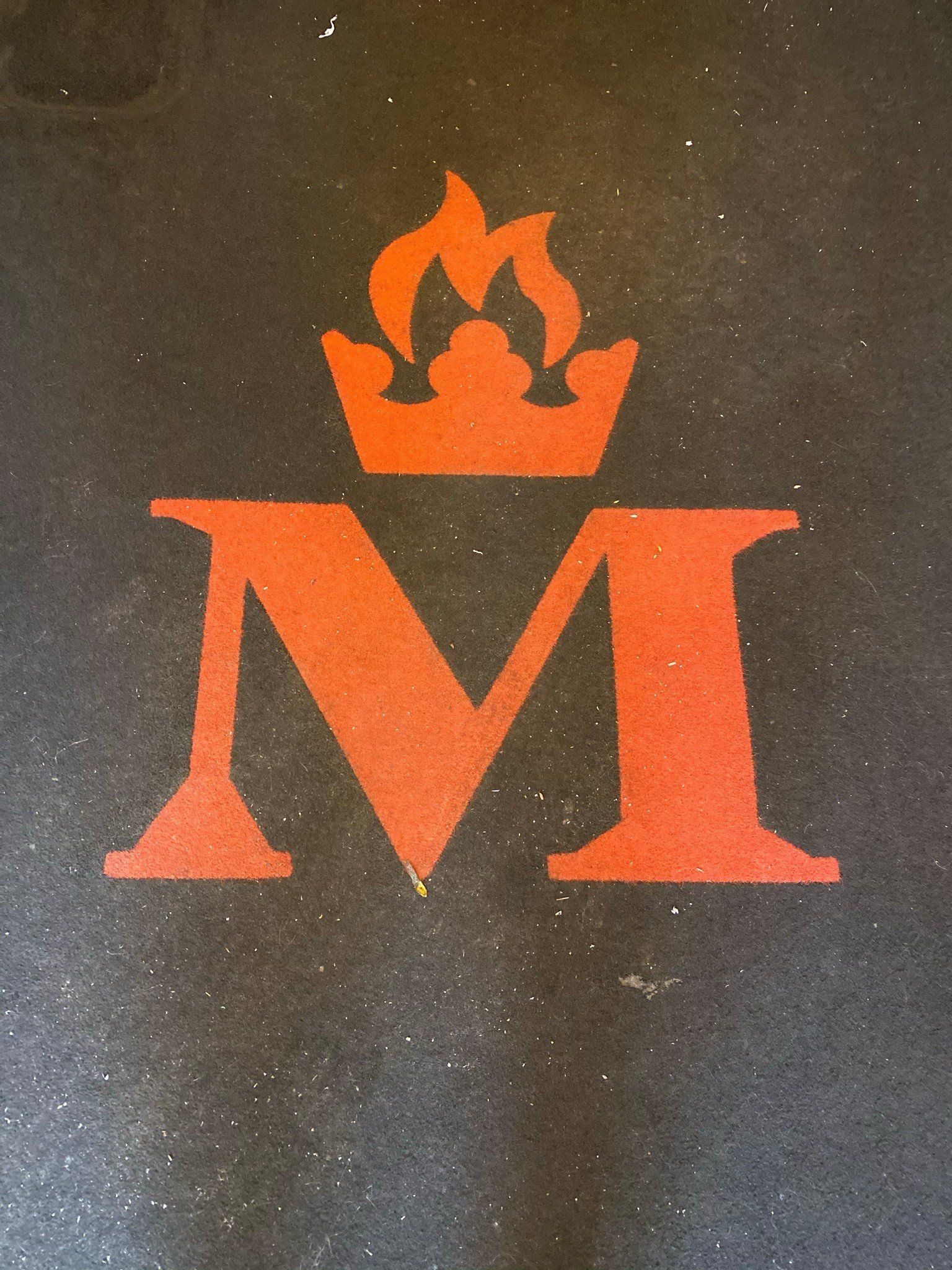 a rug with a red letter m with a crown on top of it, before cleaning