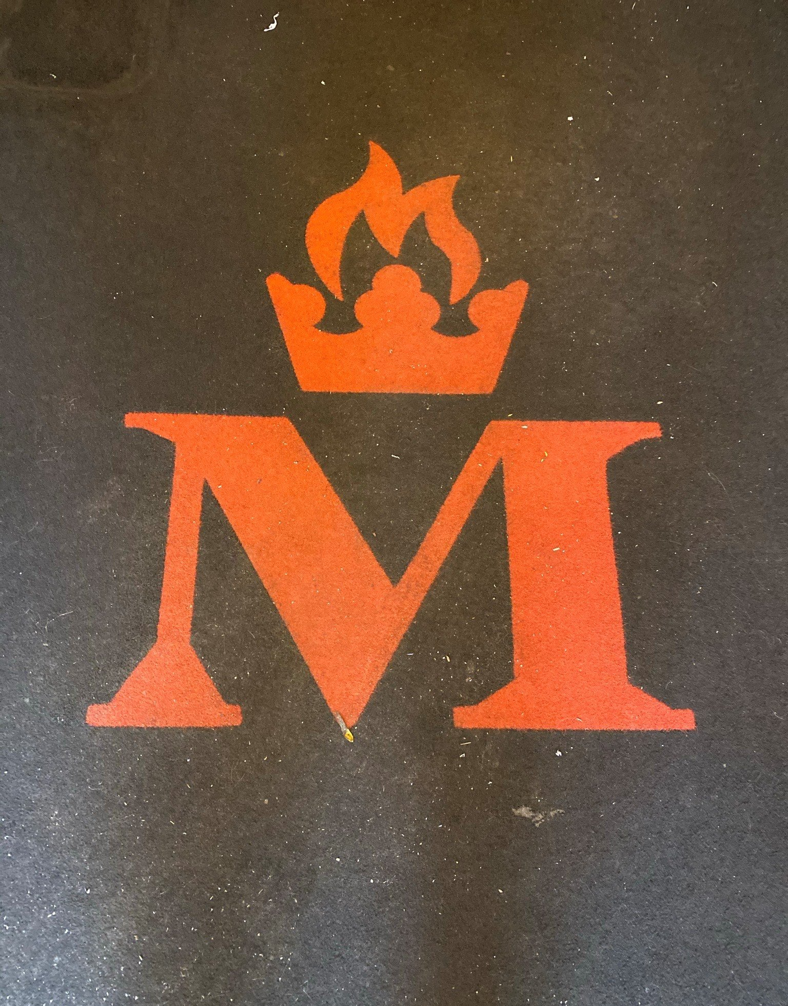a red letter m with a crown on top of it