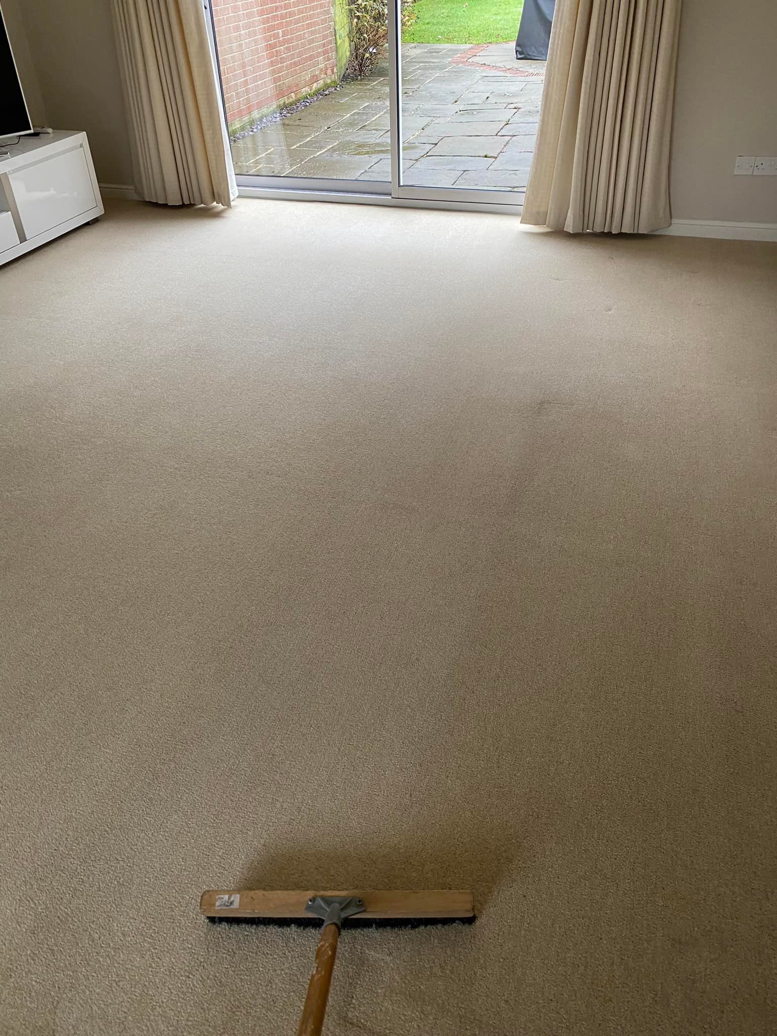 a broom is sitting on a carpeted floor in a living room .