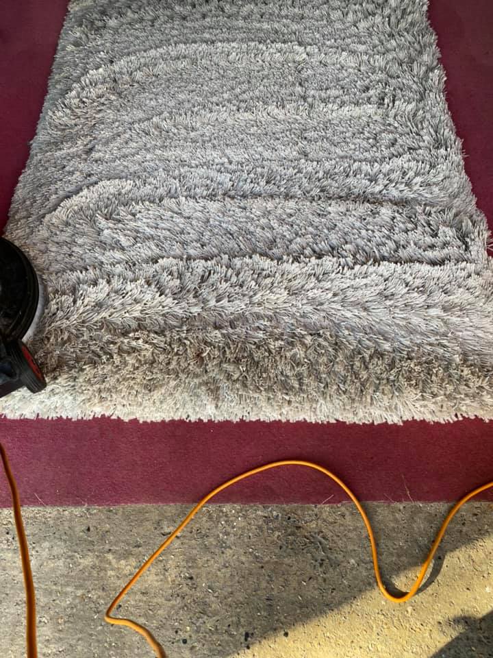 a rug is sitting on top of a red carpet next to an orange cord .