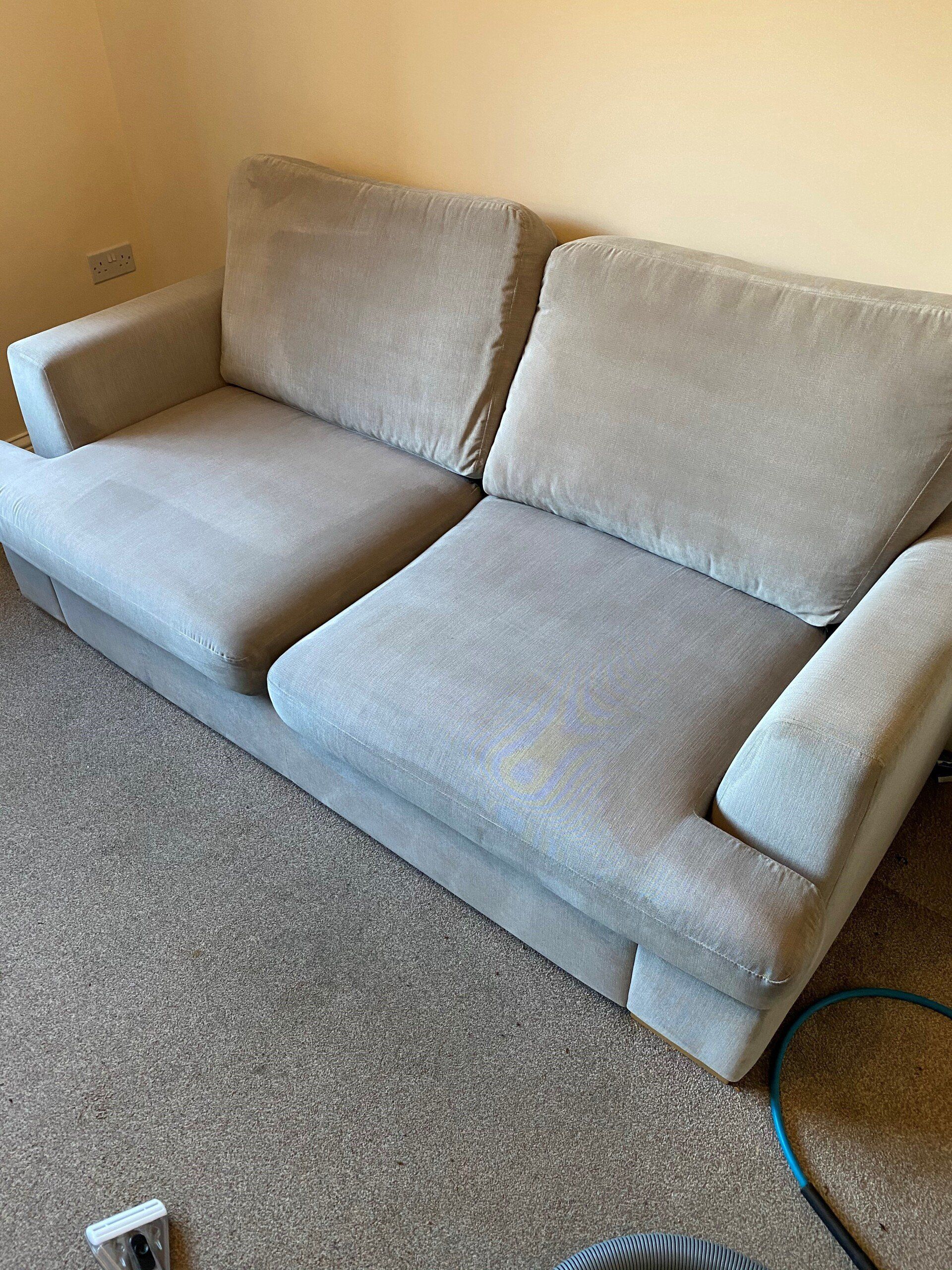 a grey couch is sitting on a carpeted floor in a living room .