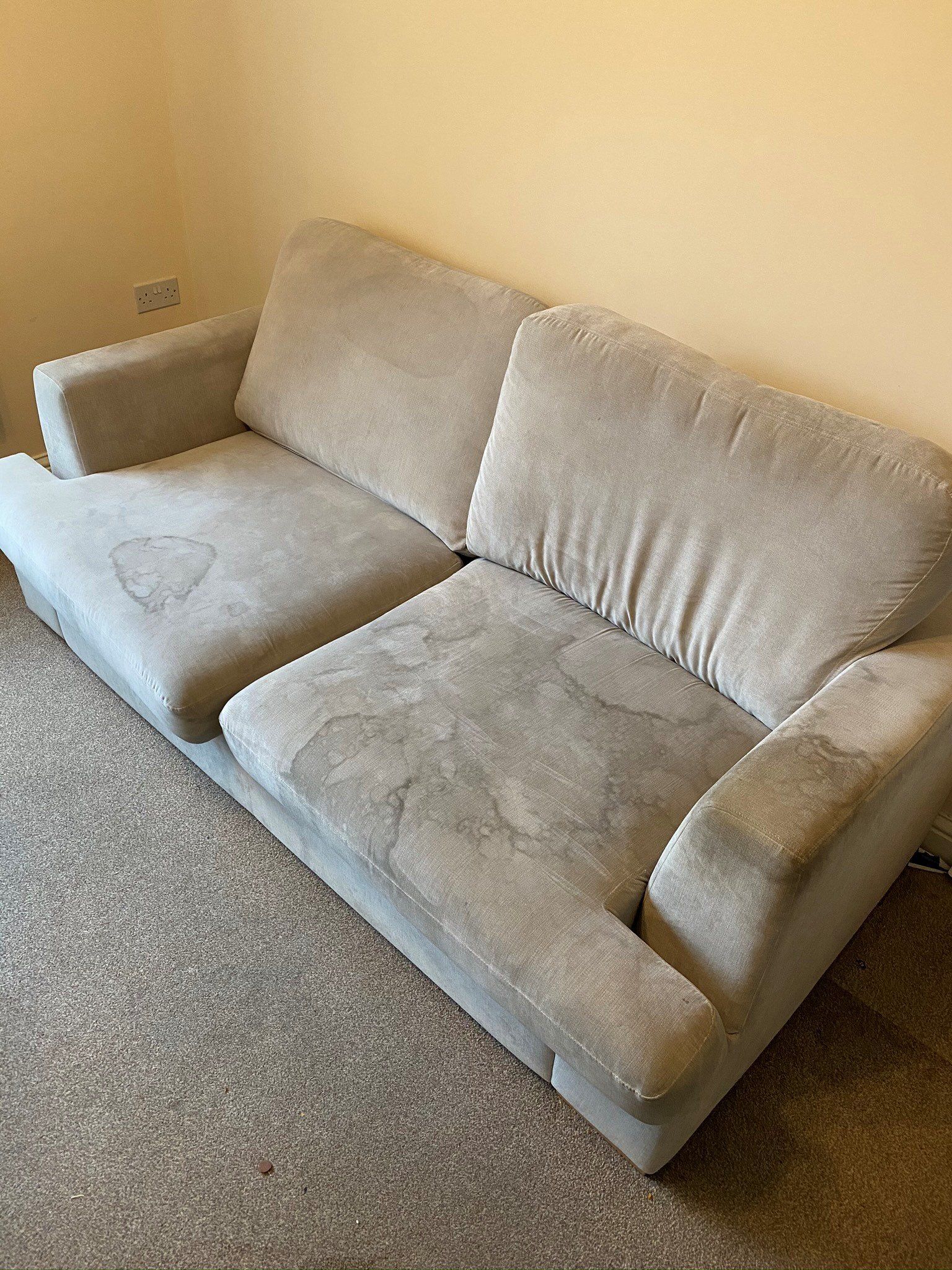 a white couch is sitting on a carpet in a living room .