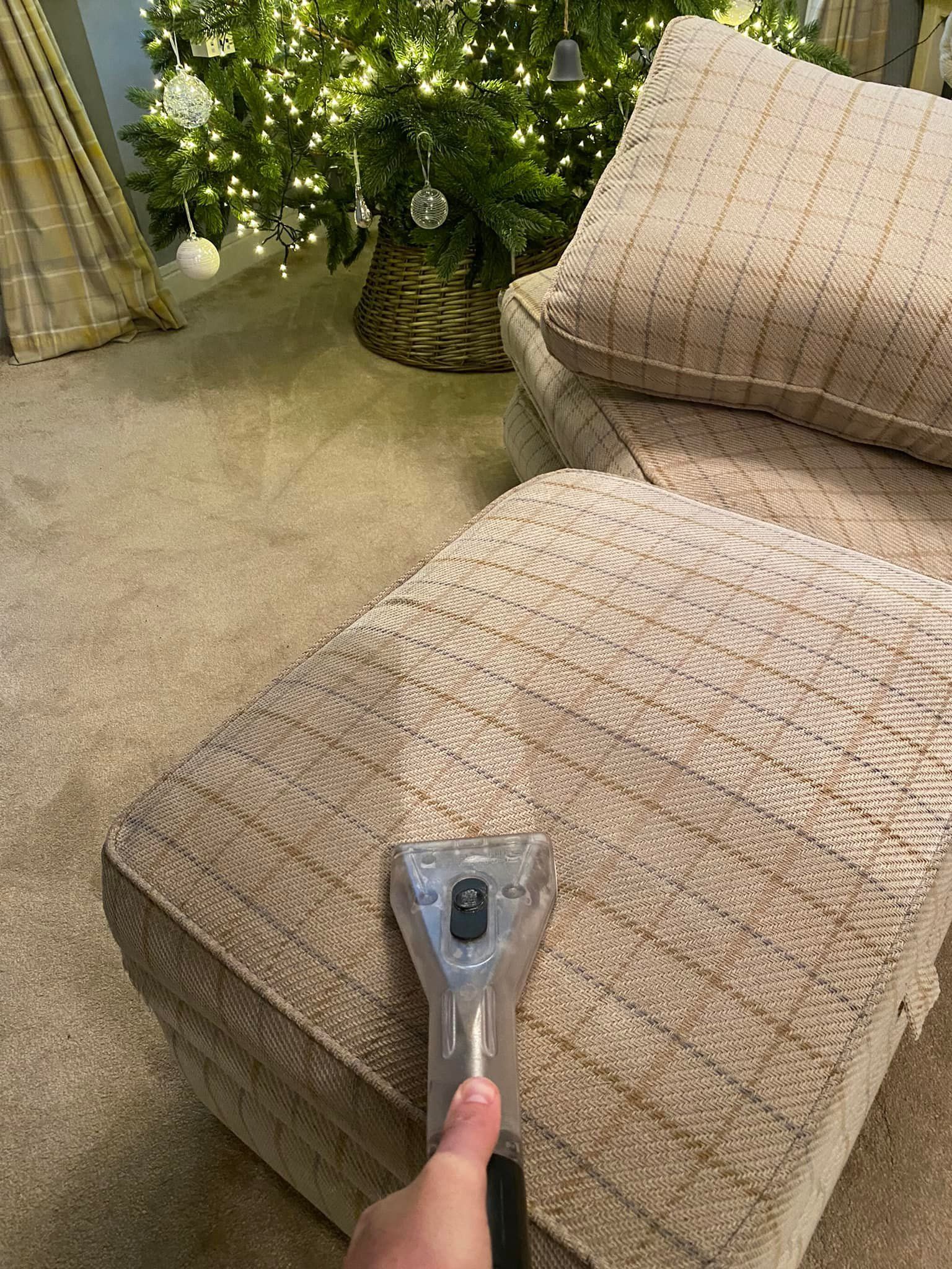a person is cleaning a chair with a vacuum cleaner in front of a christmas tree .