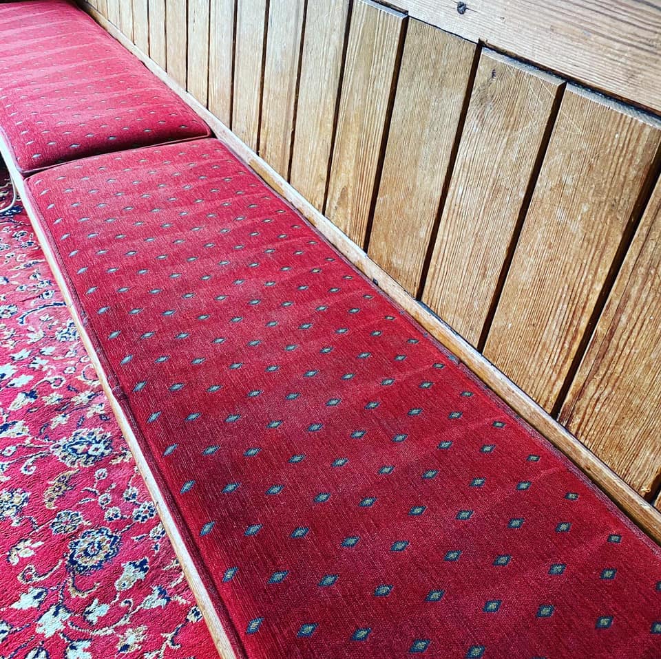 a wooden bench with a red carpet on it