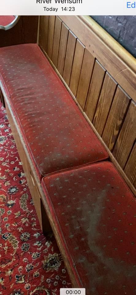 a wooden bench with red cushions in a room with a red rug .