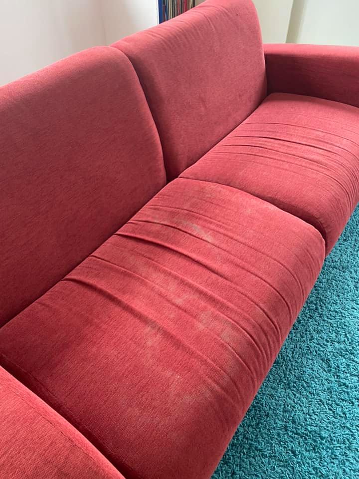 a red couch is sitting on a blue rug in a living room .