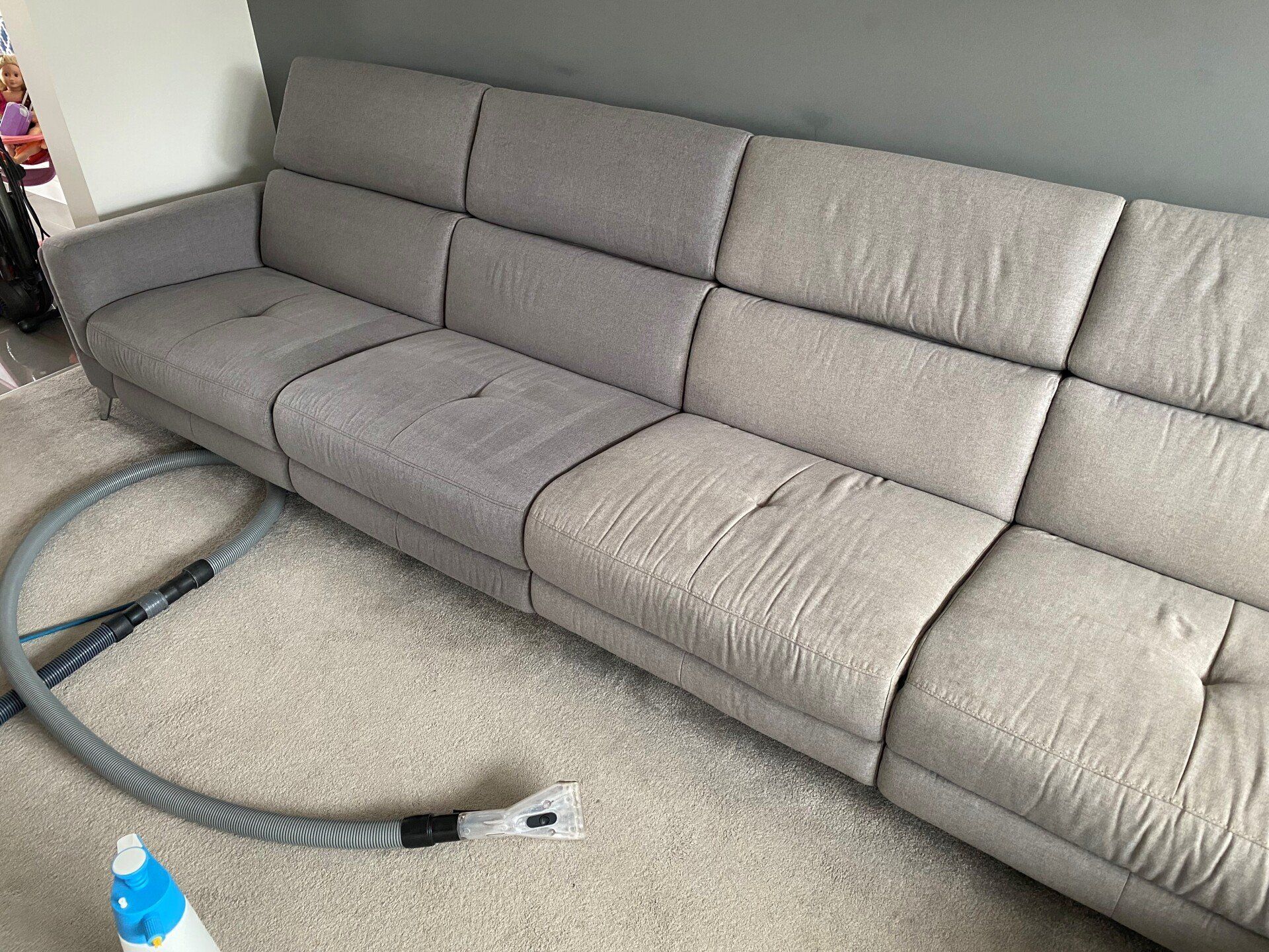 a couch is being cleaned in a living room with a vacuum cleaner .