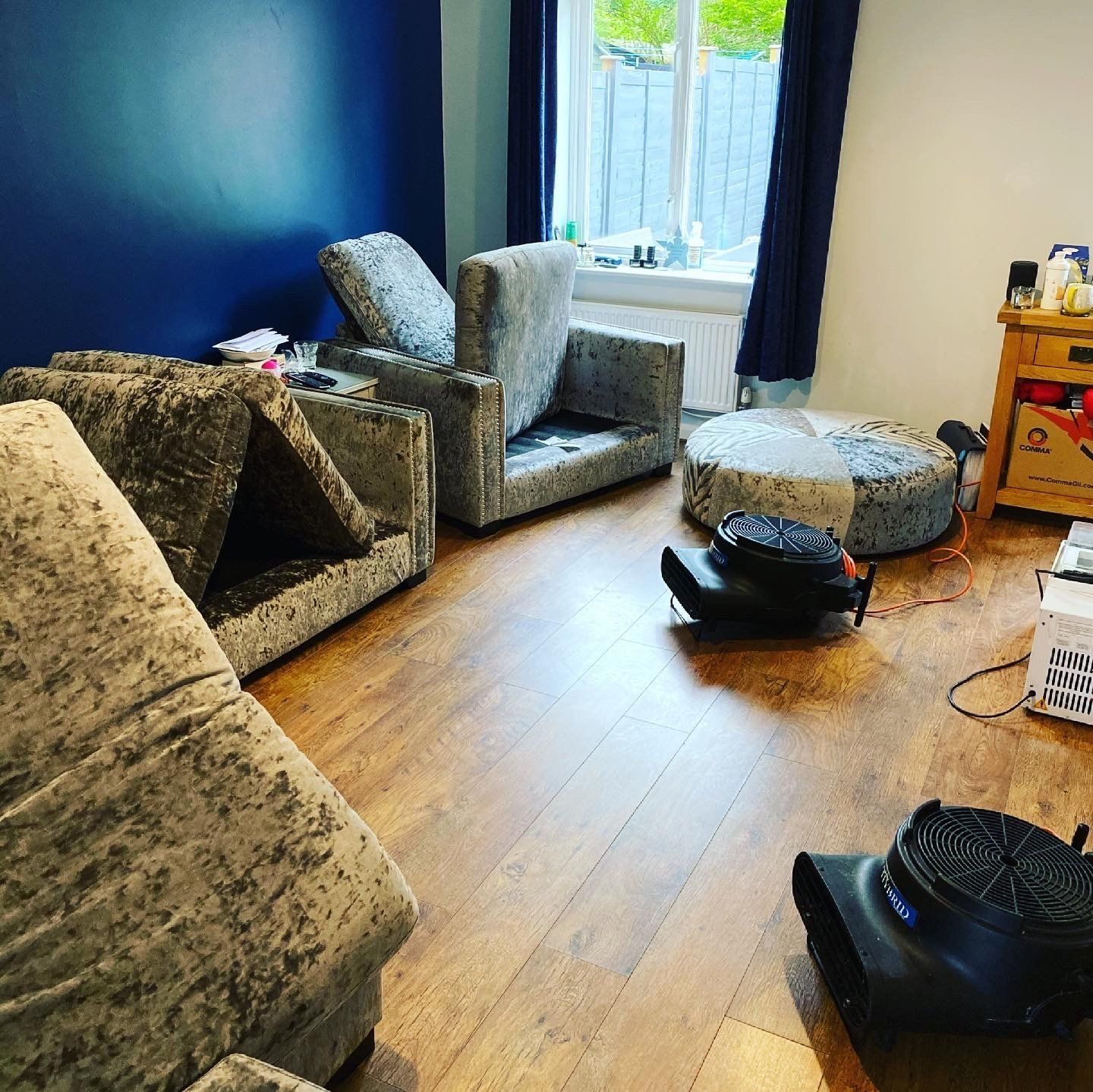 a living room with a couch , chairs , ottomans and a fan .