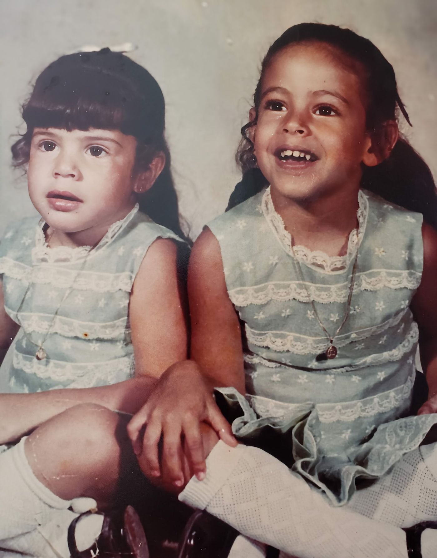 Two little girls in blue dresses are sitting next to each other
