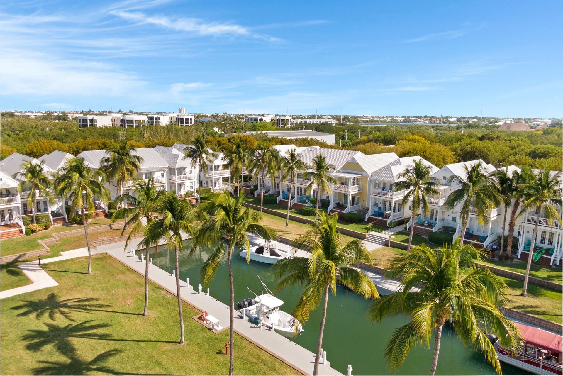 An aerial view of a tropical resort with palm trees and boats docked in the water.