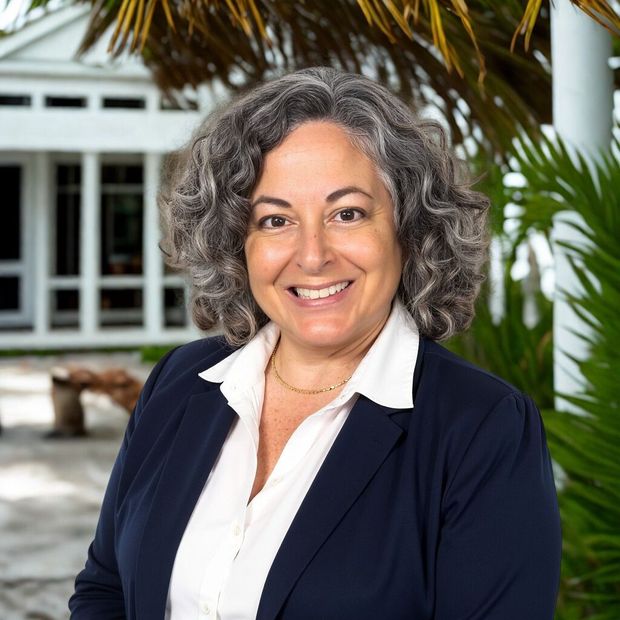 A woman with curly hair wearing a black shirt smiles for the camera