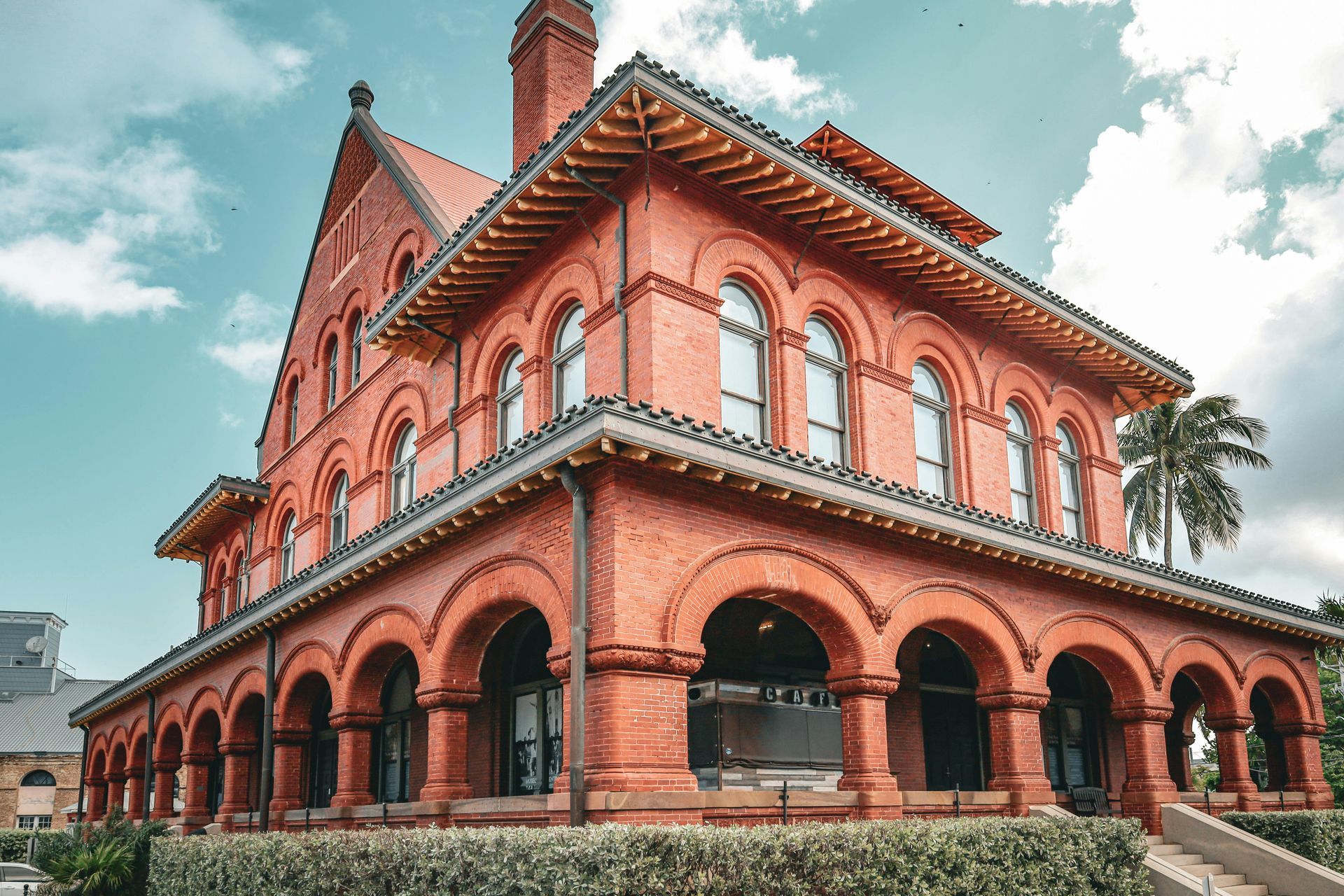 A large red brick building with arches and stairs in front of it.