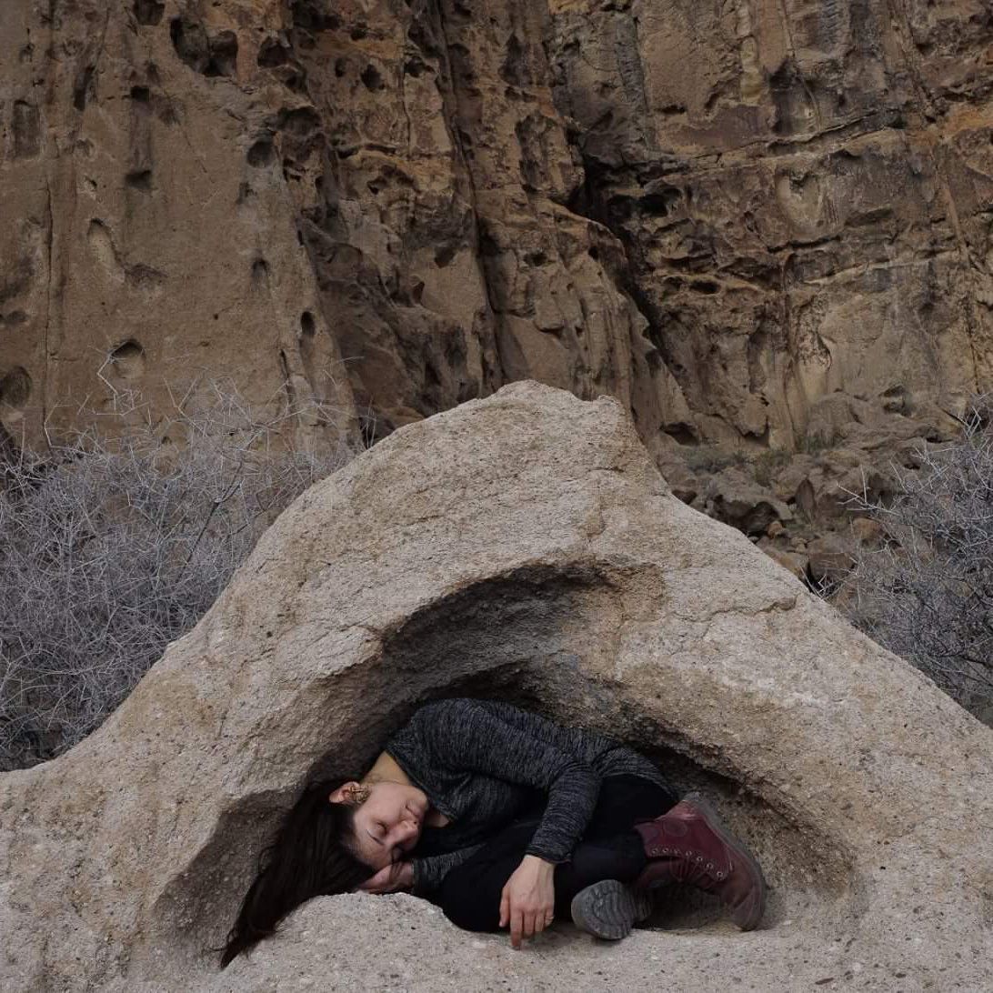Image of cristina maria fort garces crouched inside a rock.