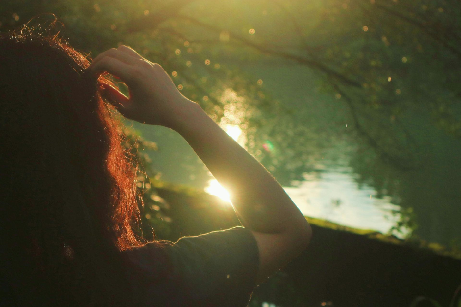 Image of the back of a person standing in front of a lake. 