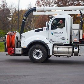 White Clean Earth truck with a smiling driver. On a road.