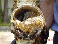 Close-up of a clogged pipe, showing a build-up of grime and debris obstructing the passage.