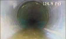 Inside view of a pipe with a yellow liquid pooling at the bottom and dark, murky liquid above.
