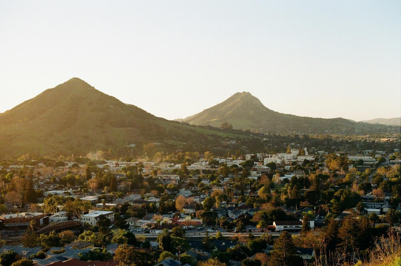 View of a town nestled among rolling hills, bathed in warm sunlight.