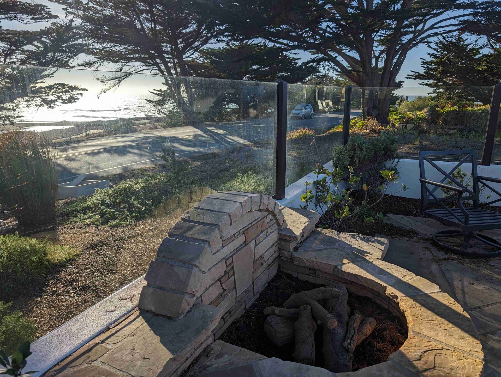 A fire pit on a patio with a view of the ocean.