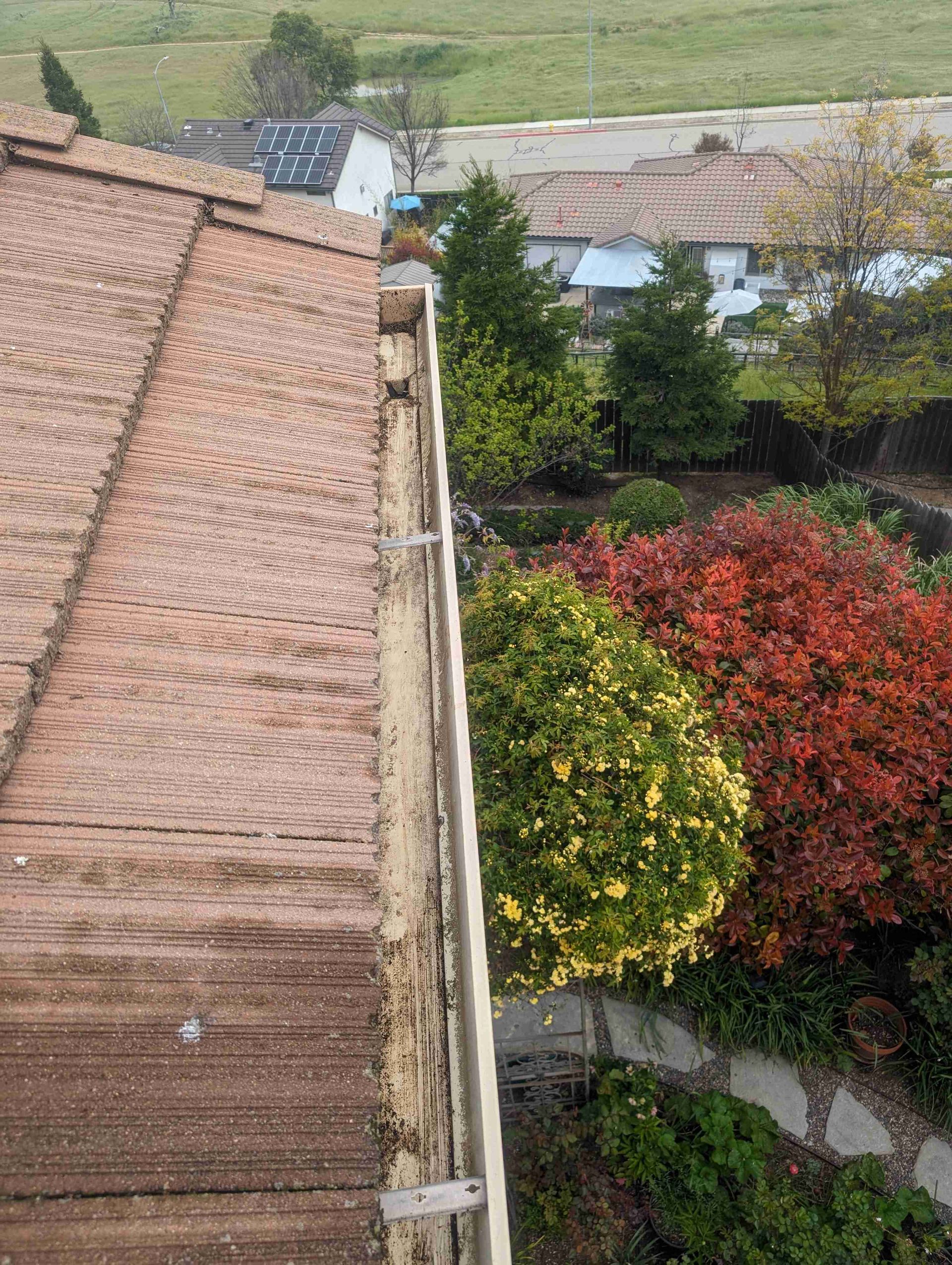 Aerial view of a roof with a gutter and trees in the background.