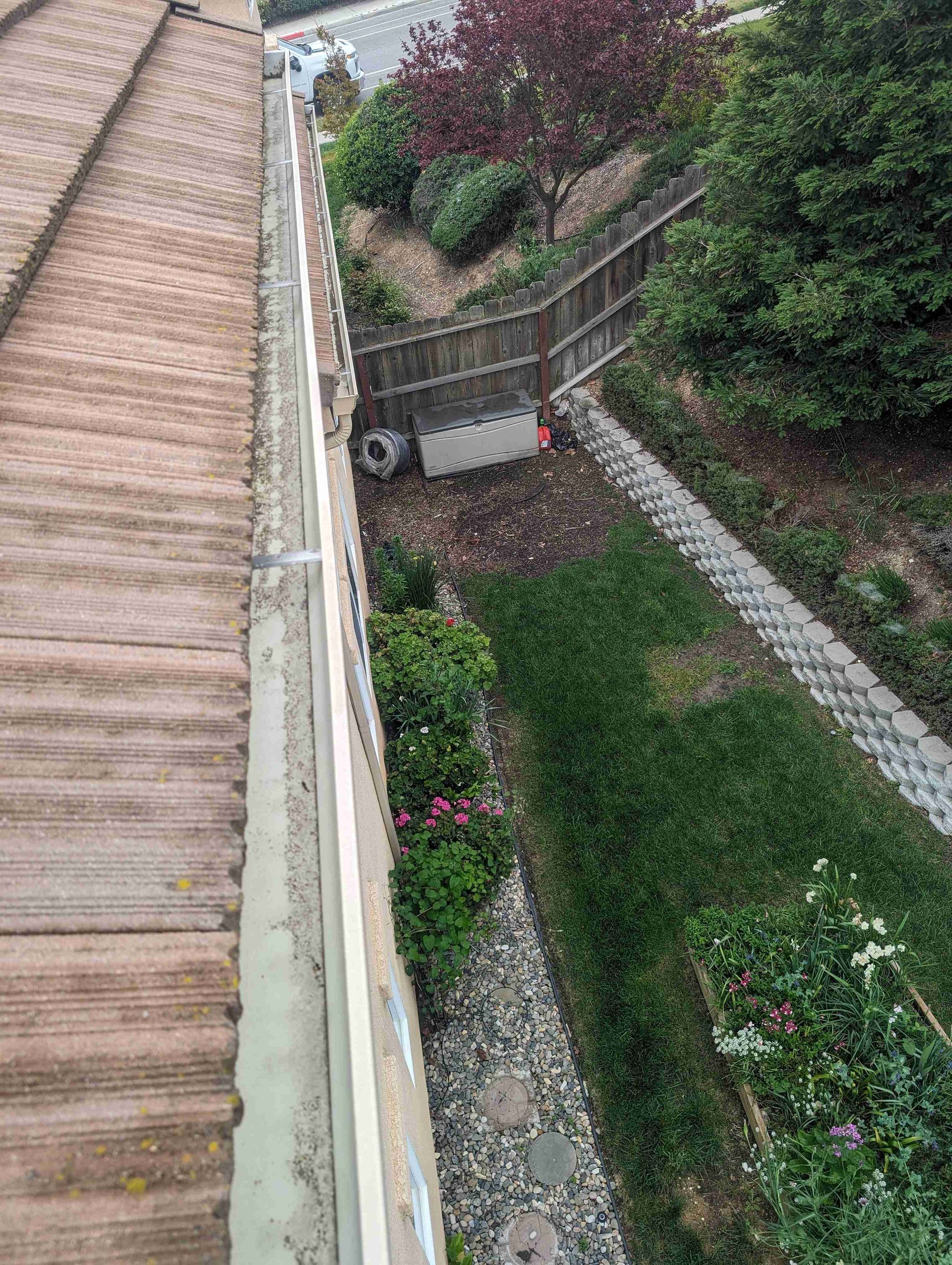 An aerial view of a gutter on a roof next to a garden.