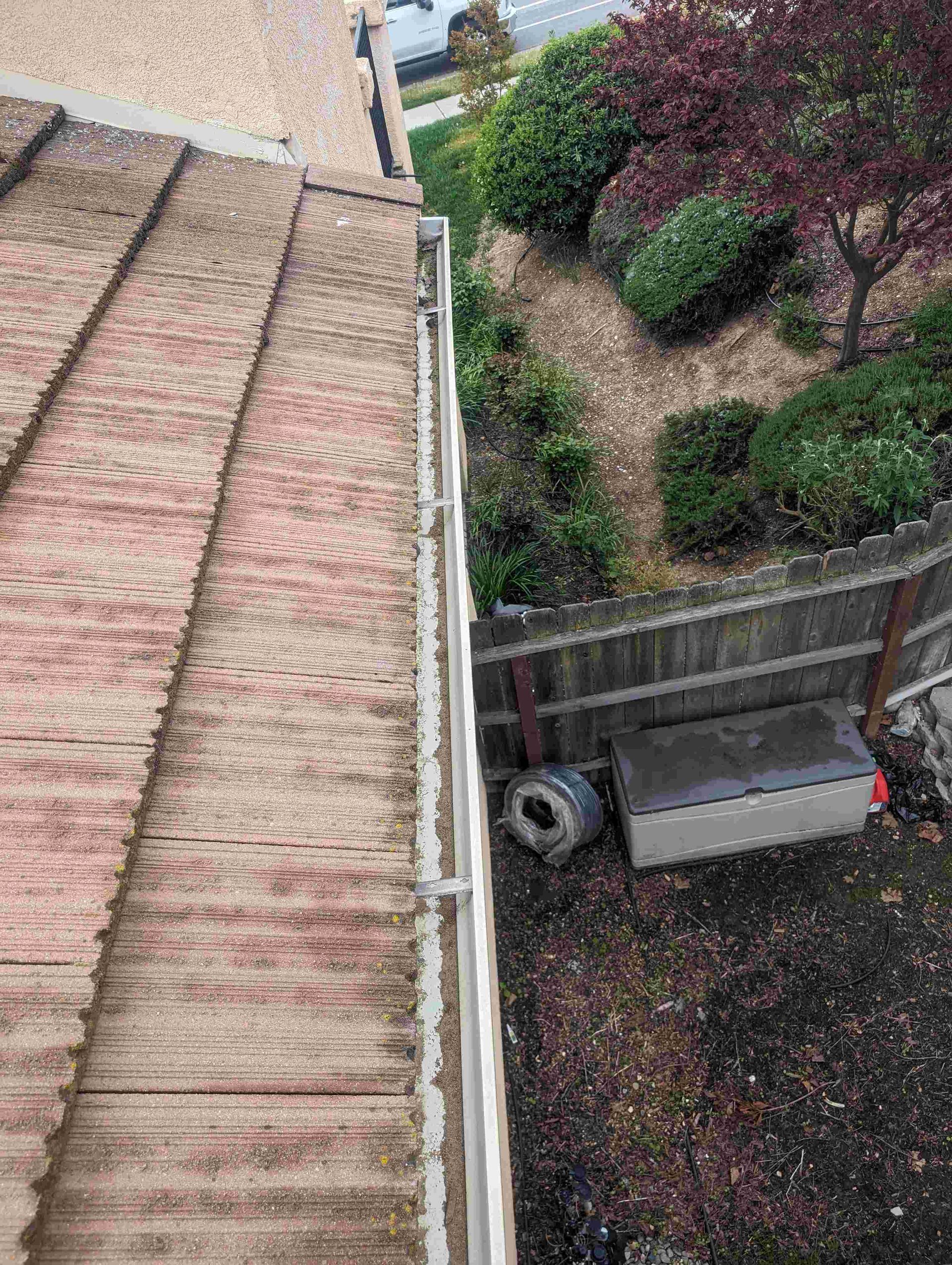Aerial view of a gutter on a roof next to a fence.