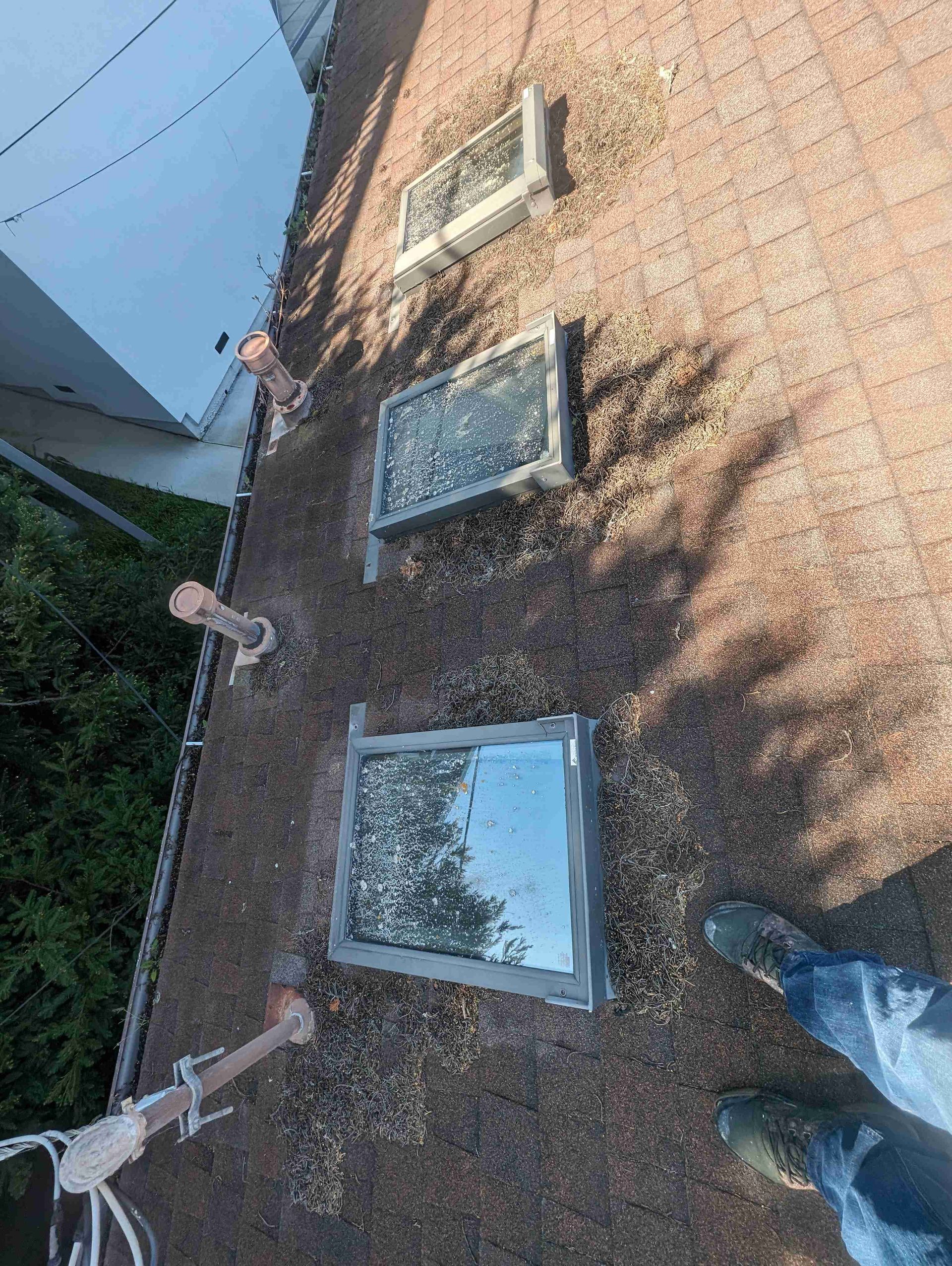 Person is standing on top of a roof with three skylights.