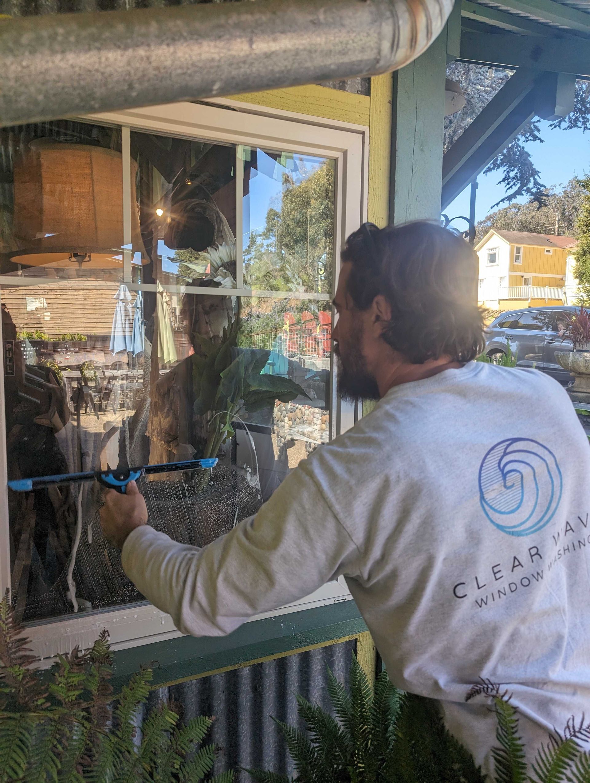 Man is cleaning a window with a squeegee.