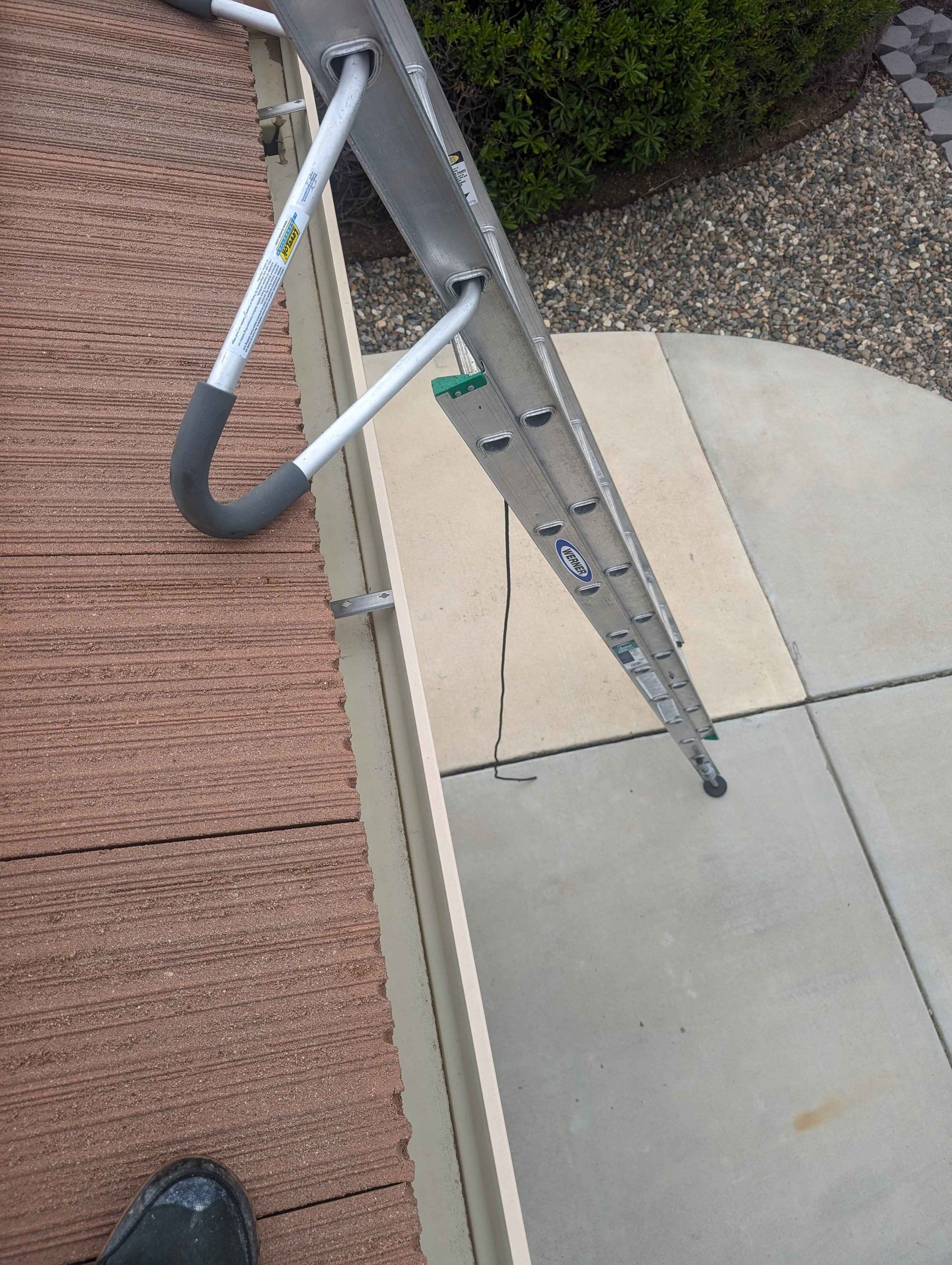 Person is standing next to a ladder on a sidewalk.