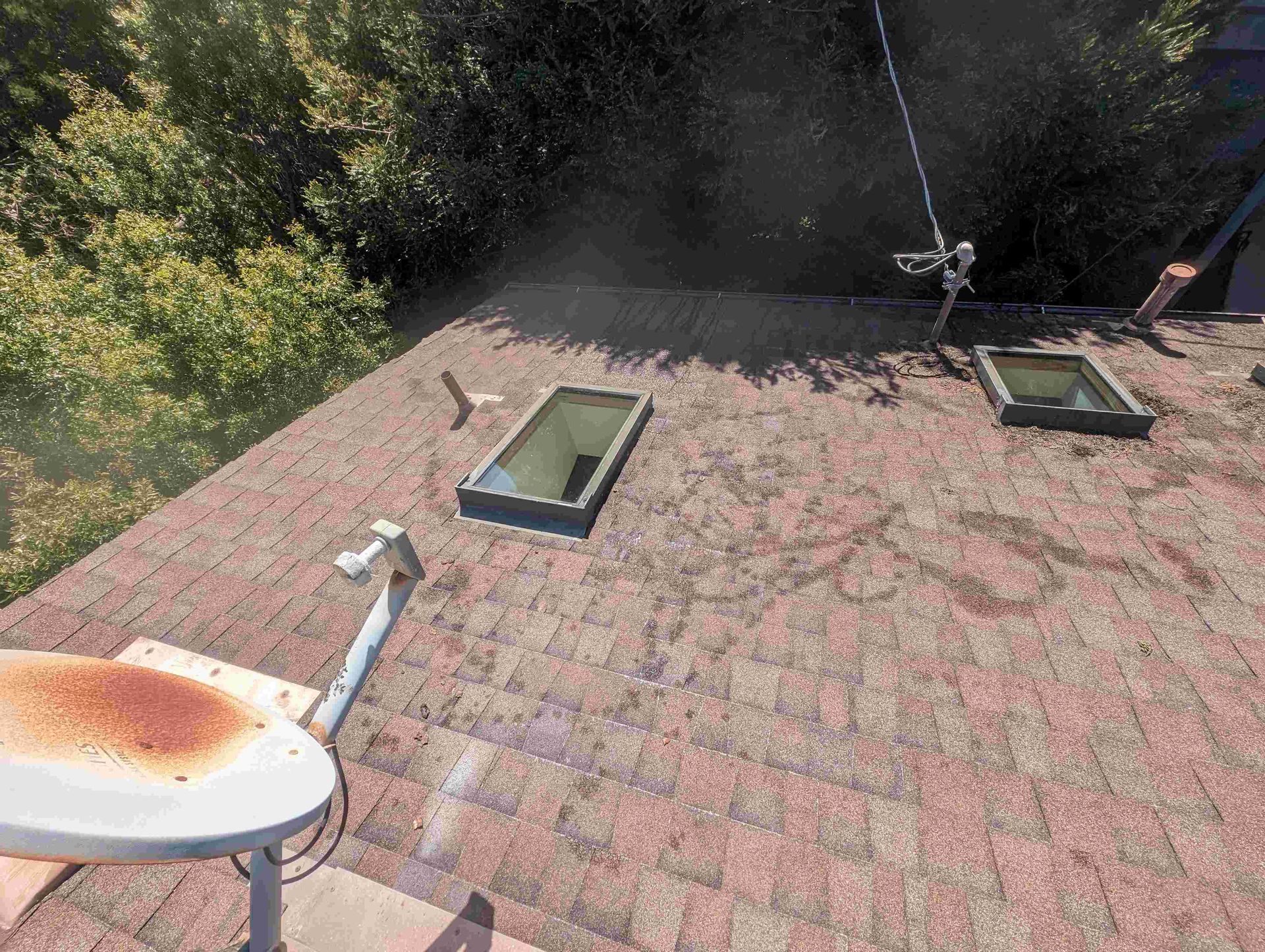 Roof with two skylights and a satellite dish on it.