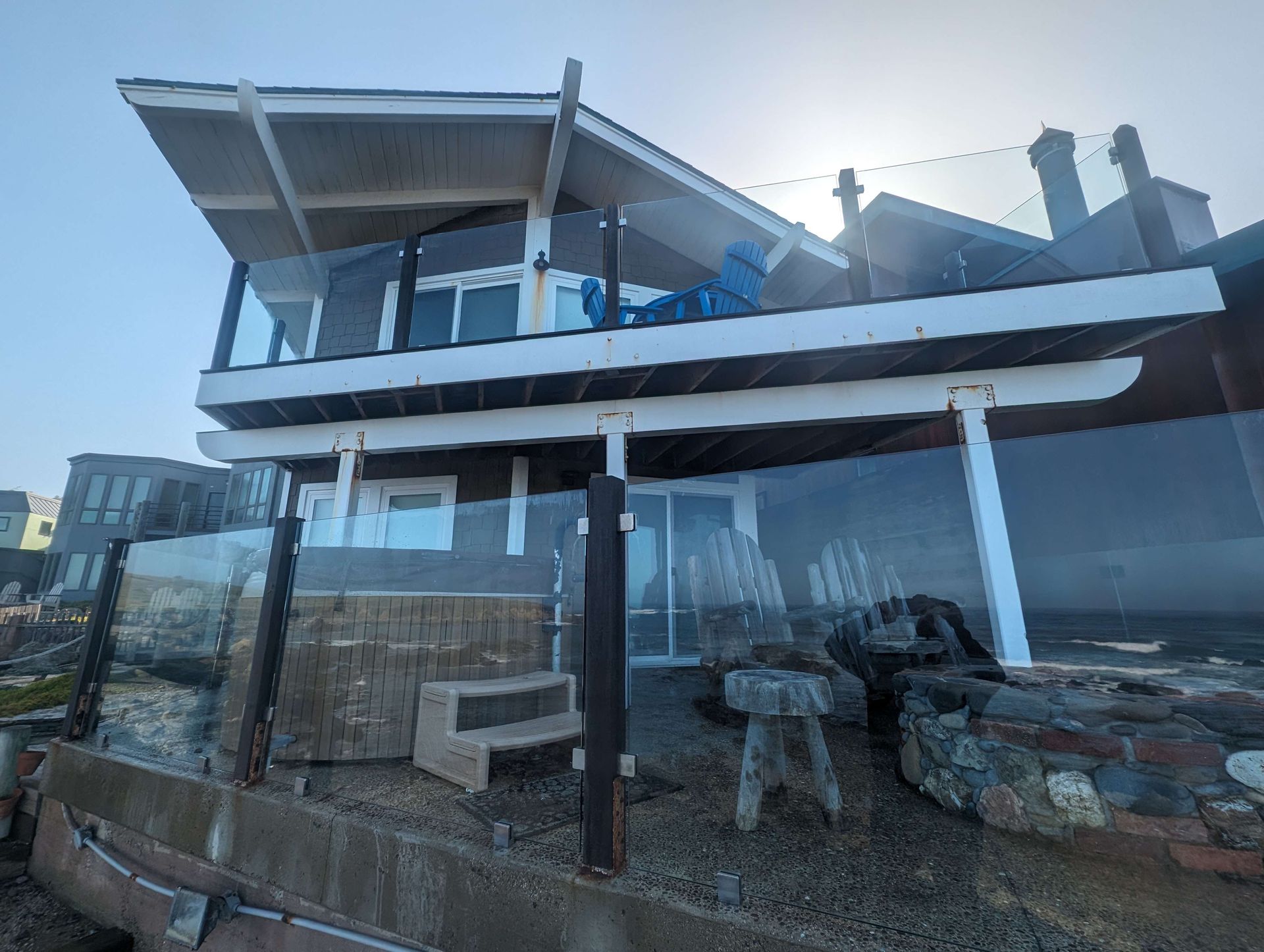 Large house with a balcony on top of it is on the beach.