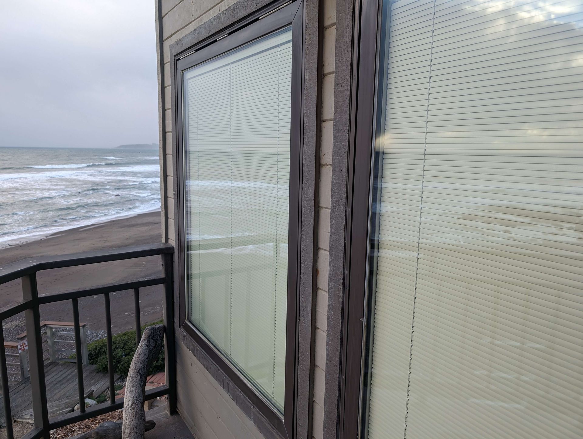 A window with blinds on it looking out to the ocean.