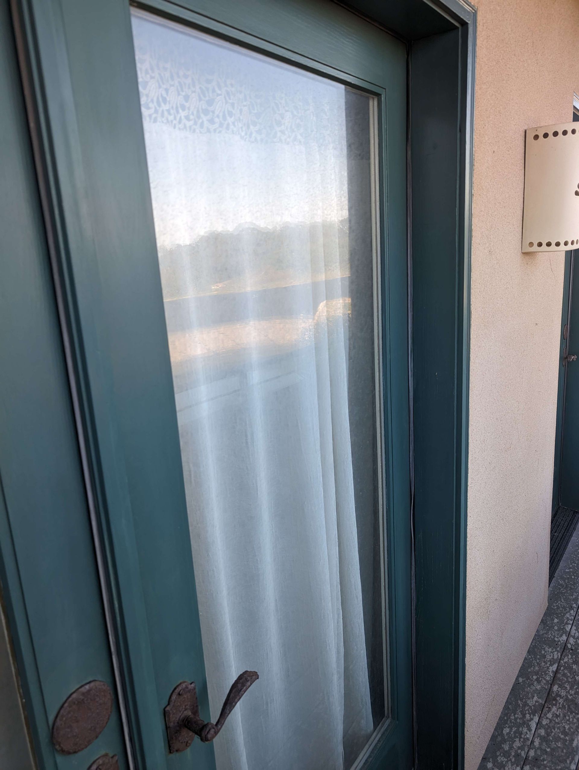 A blue door with a white curtain hanging on it.