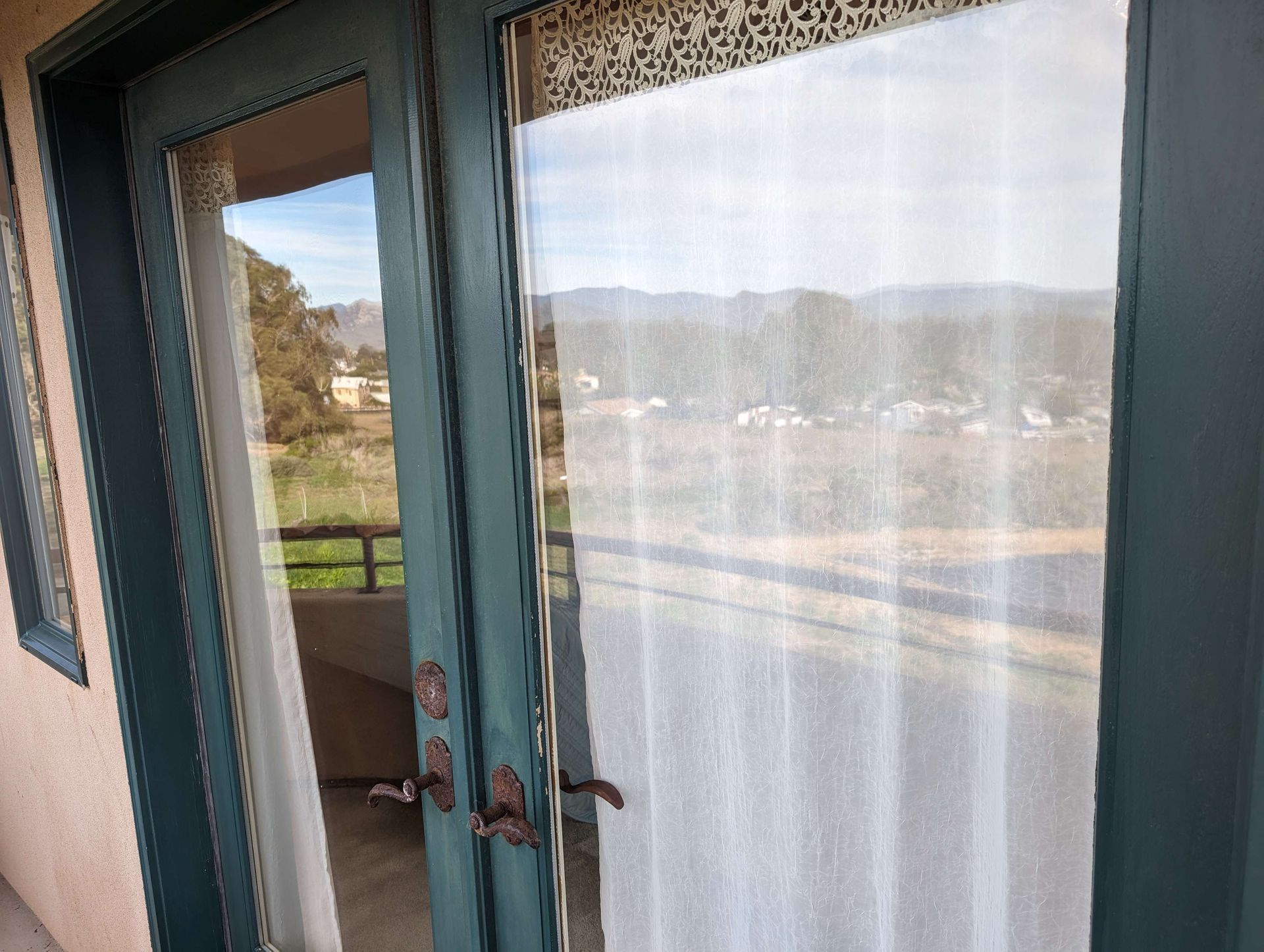 A sliding glass door with a white curtain is open to a balcony.