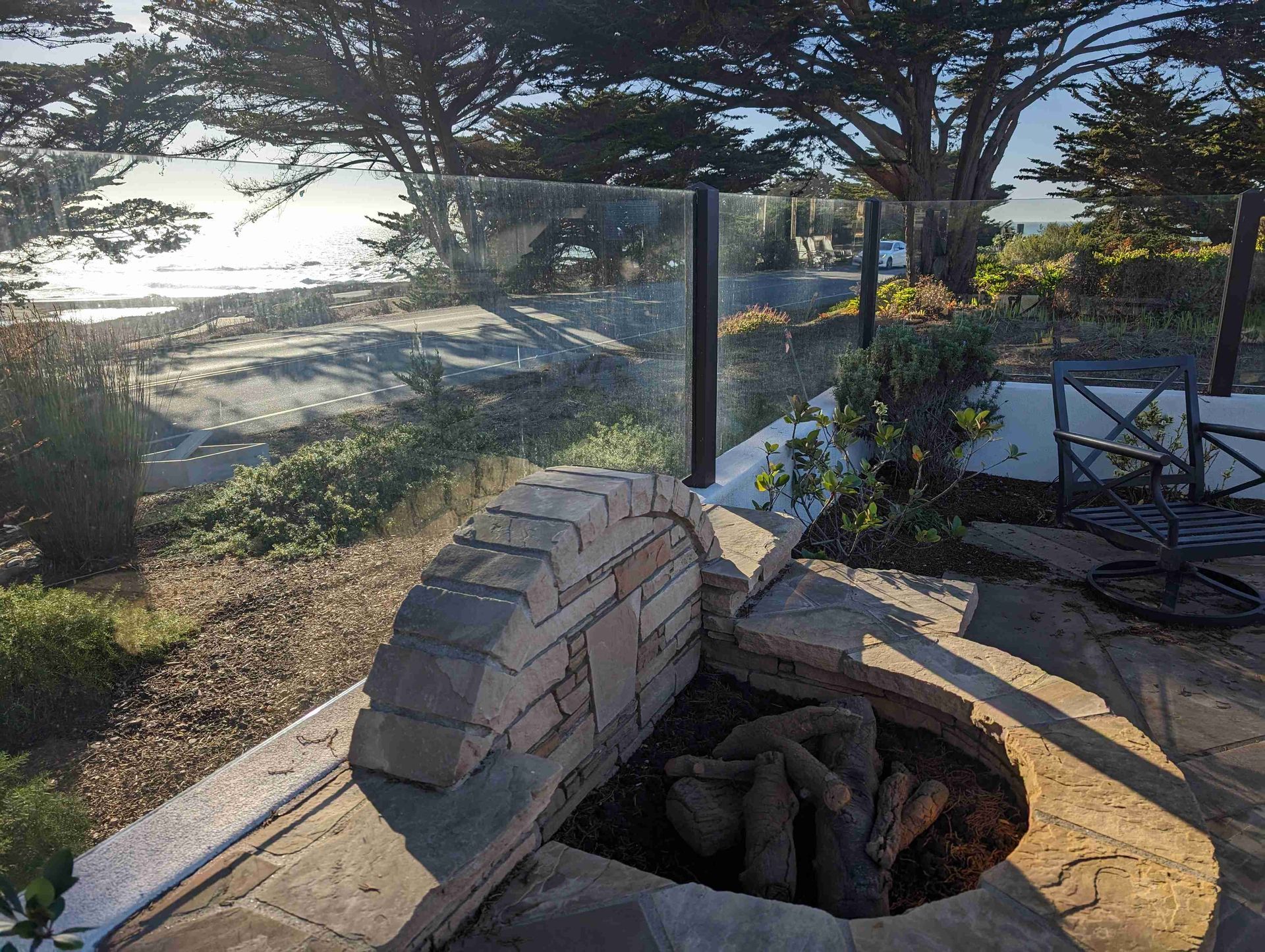 A fire pit with a view of the ocean and trees in the background.