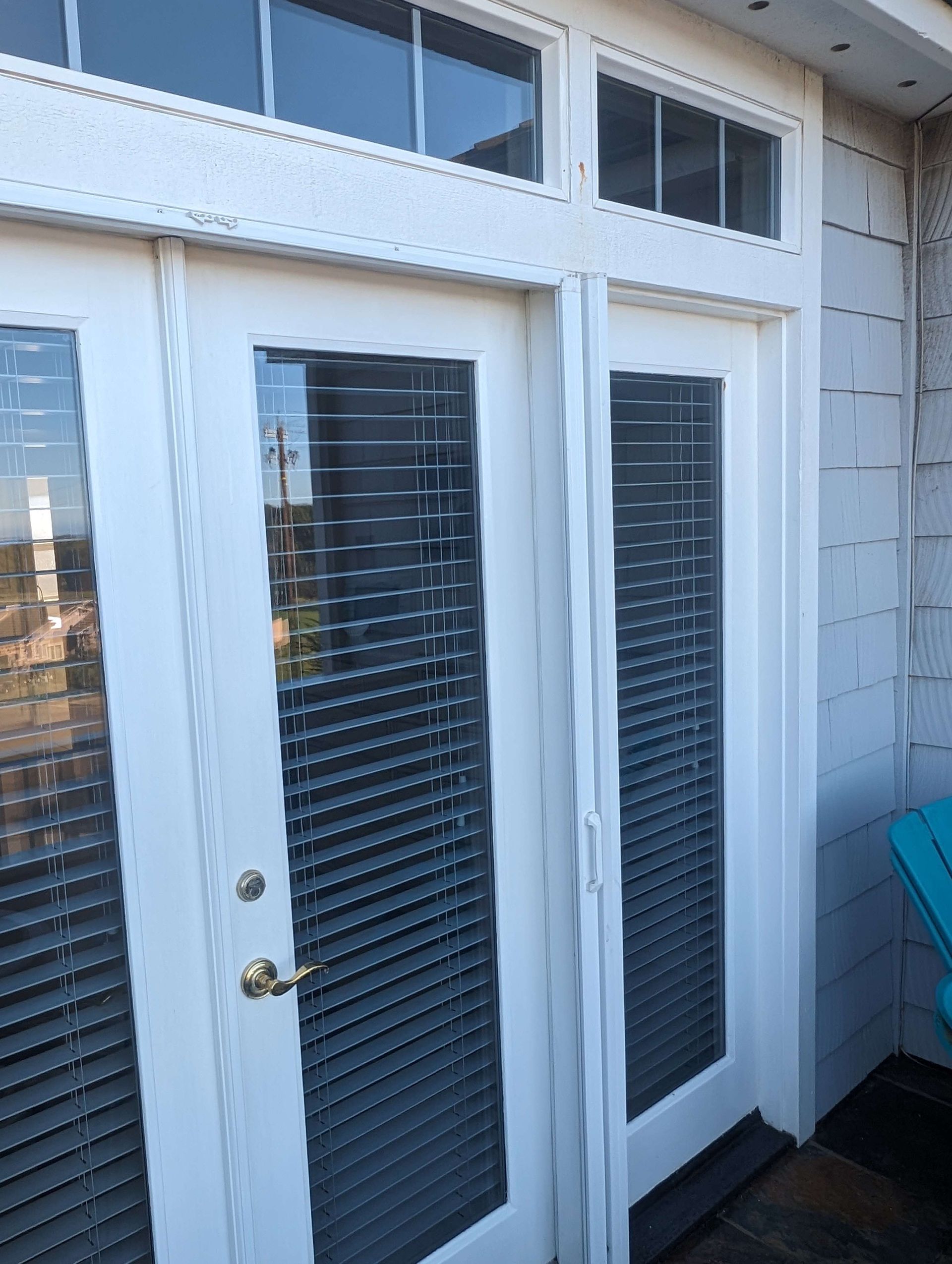 A pair of white french doors with blinds on them.