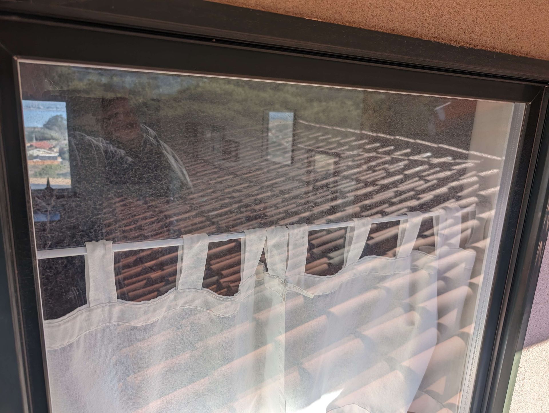 A window with a reflection of a roof in it.
