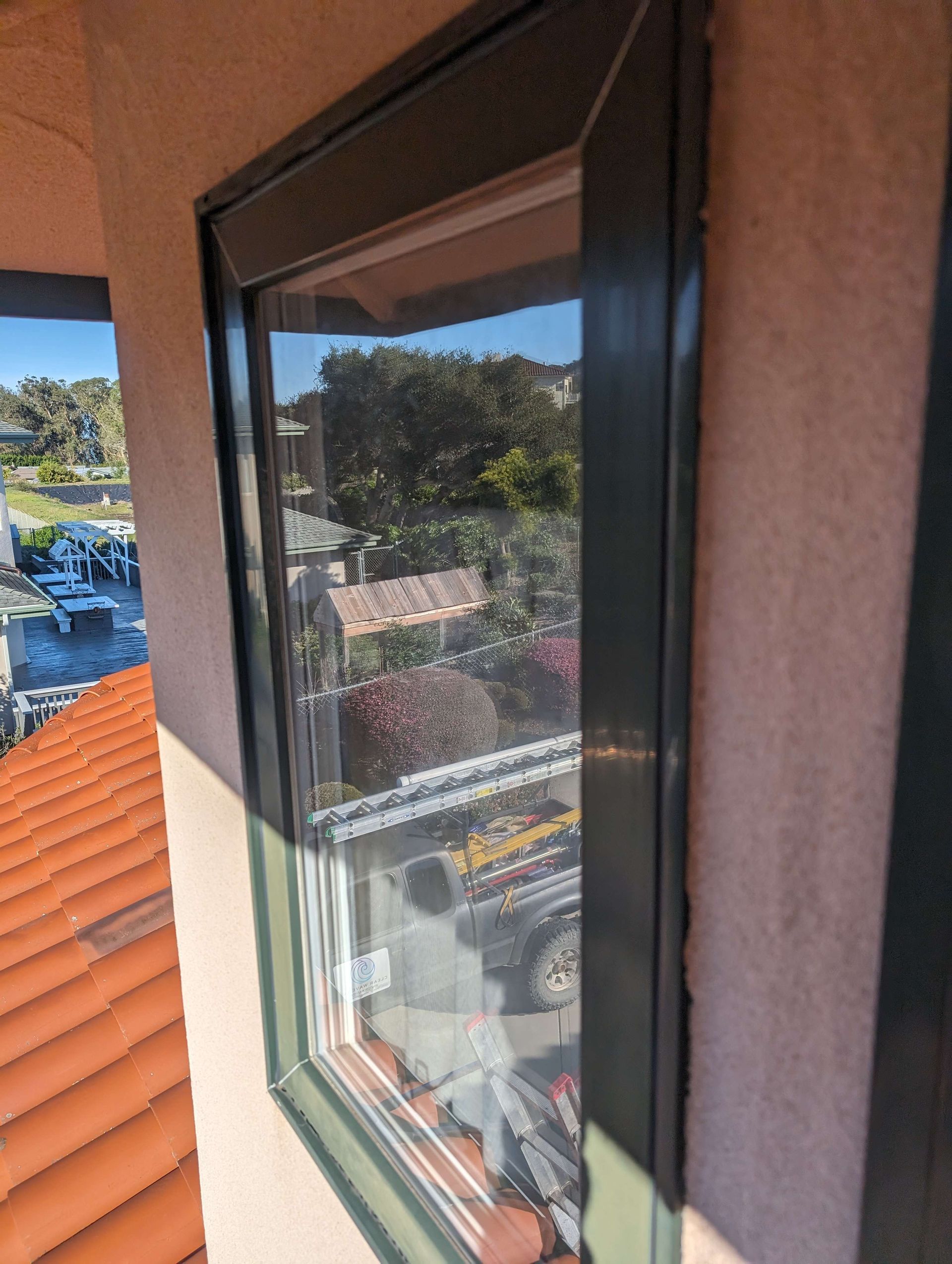 A window on the side of a building with a view of a city.