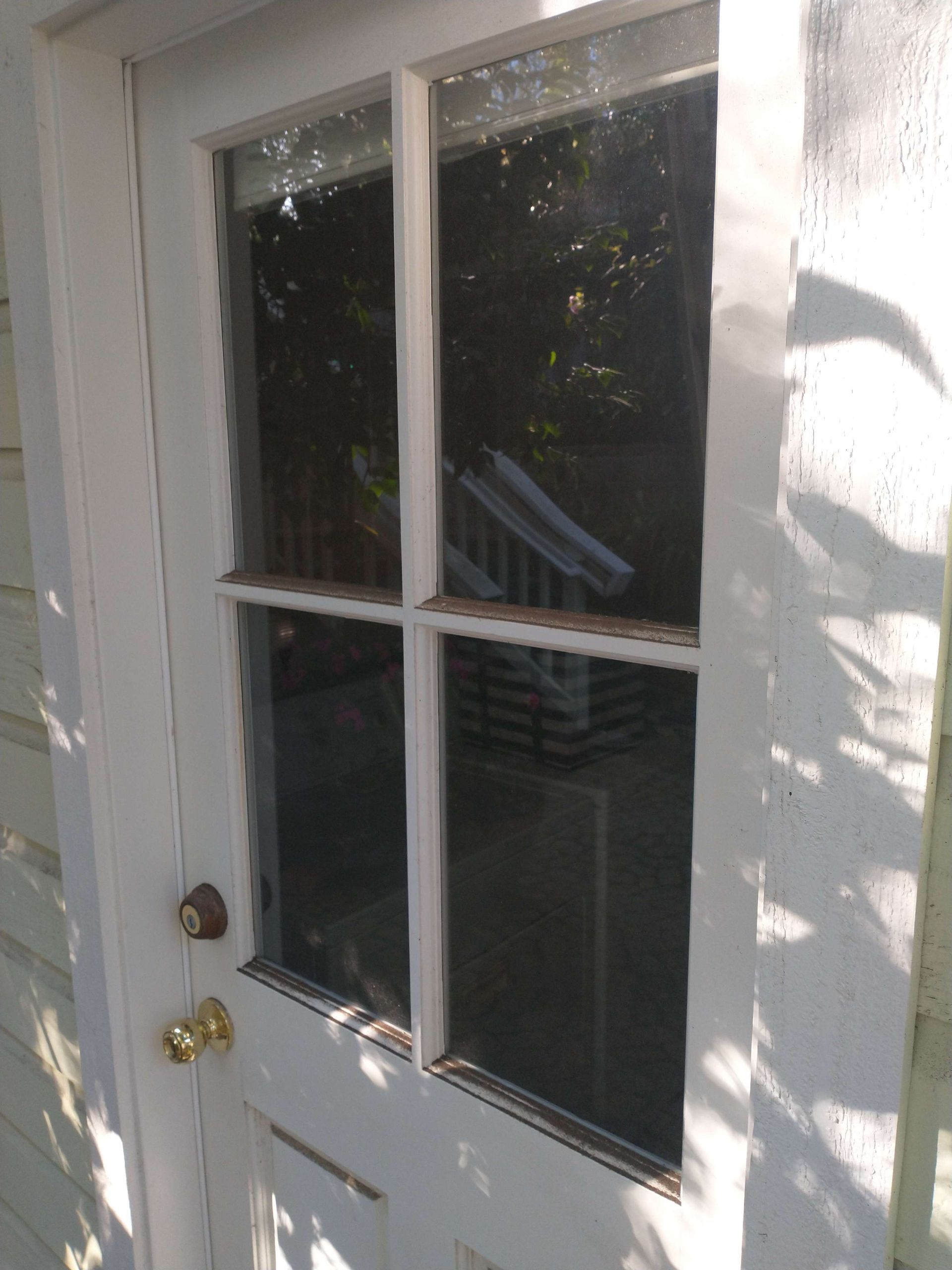 A white door with four windows and a gold knob