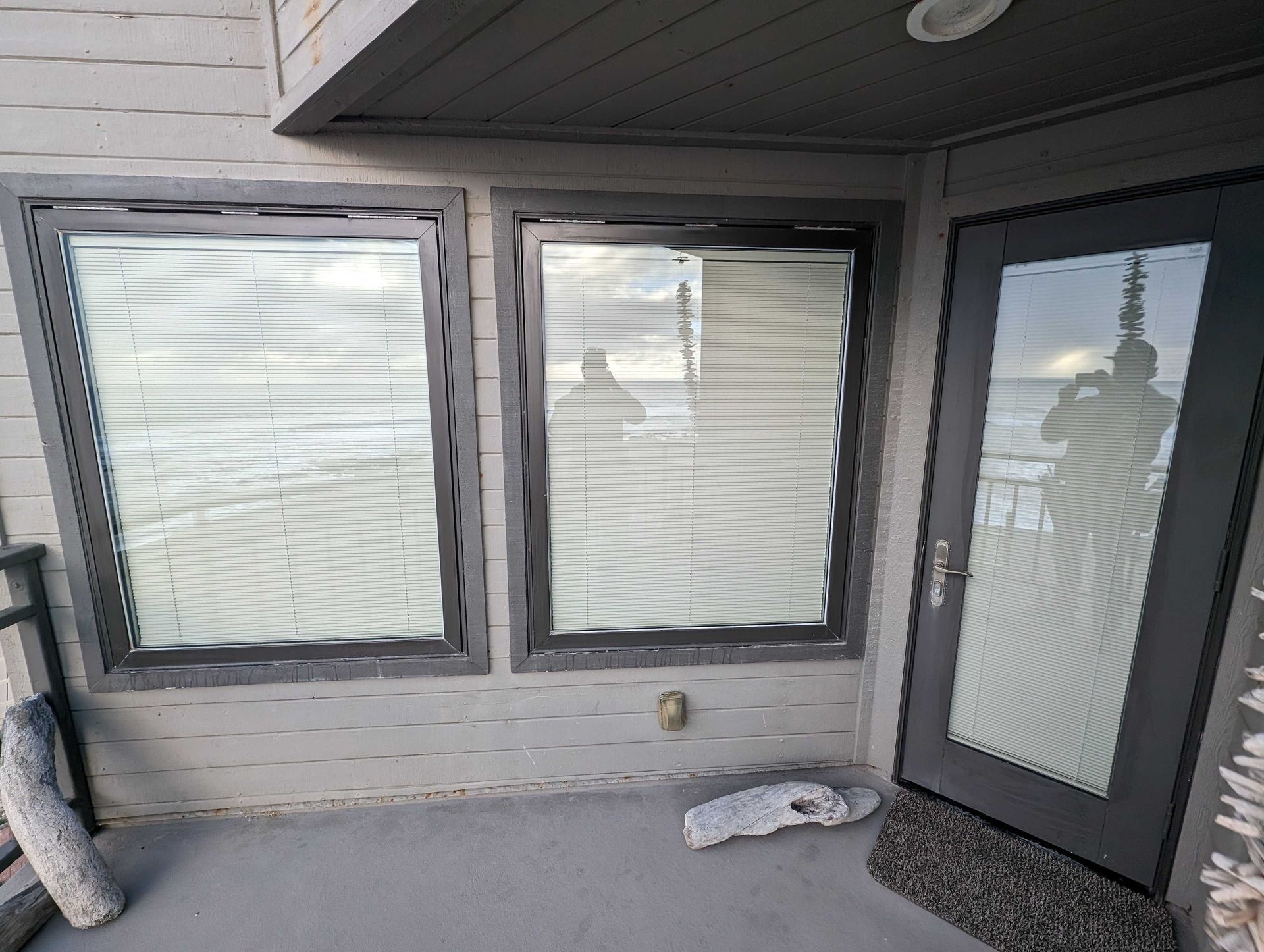 A balcony with three windows and a door with blinds on it.