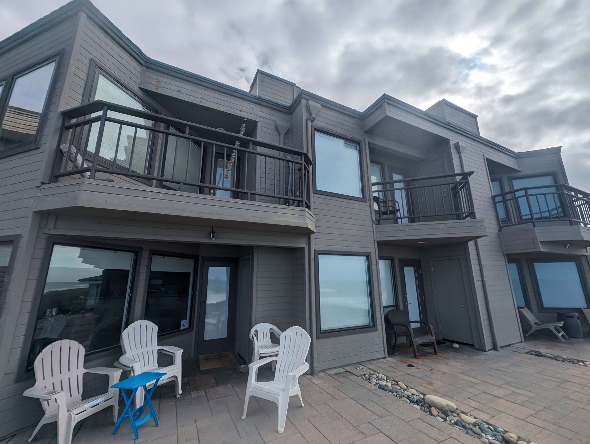 A large house with a balcony and chairs in front of it.