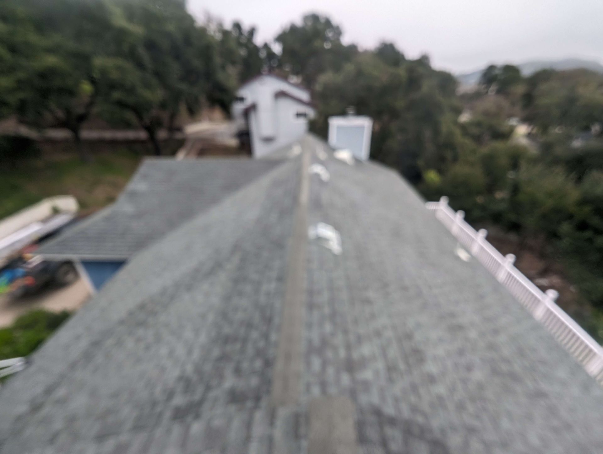 An aerial view of a roof of a house with trees in the background.